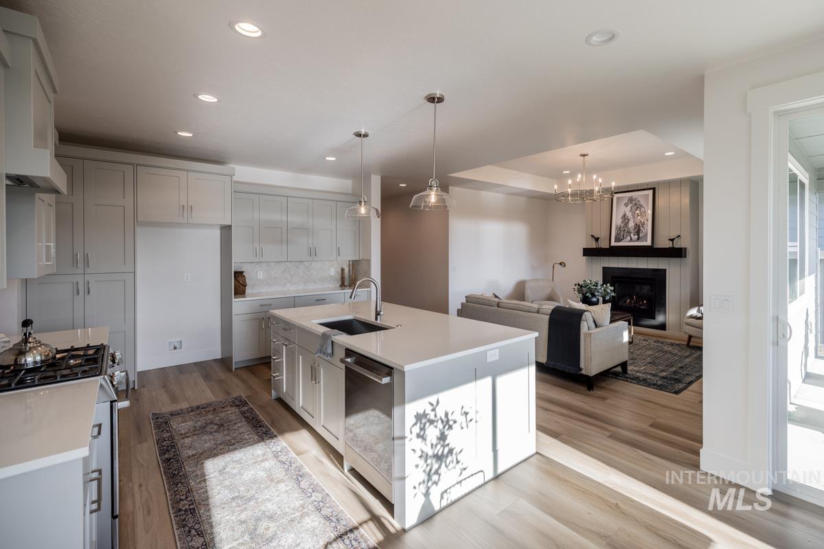 Kitchen featuring a large fireplace, pendant lighting, open floor plan, a chandelier, and appliances with stainless steel finishes