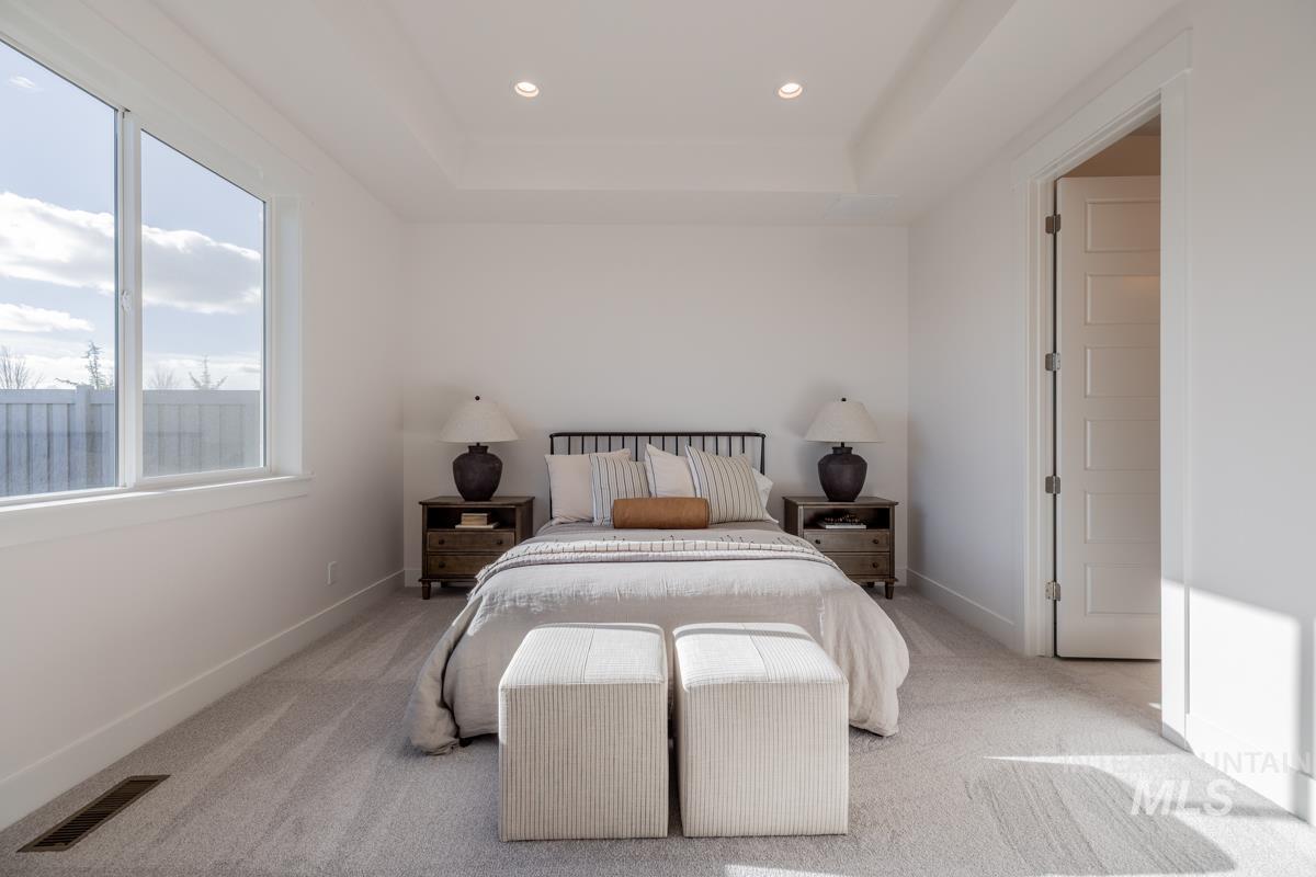 Carpeted bedroom featuring recessed lighting and a tray ceiling