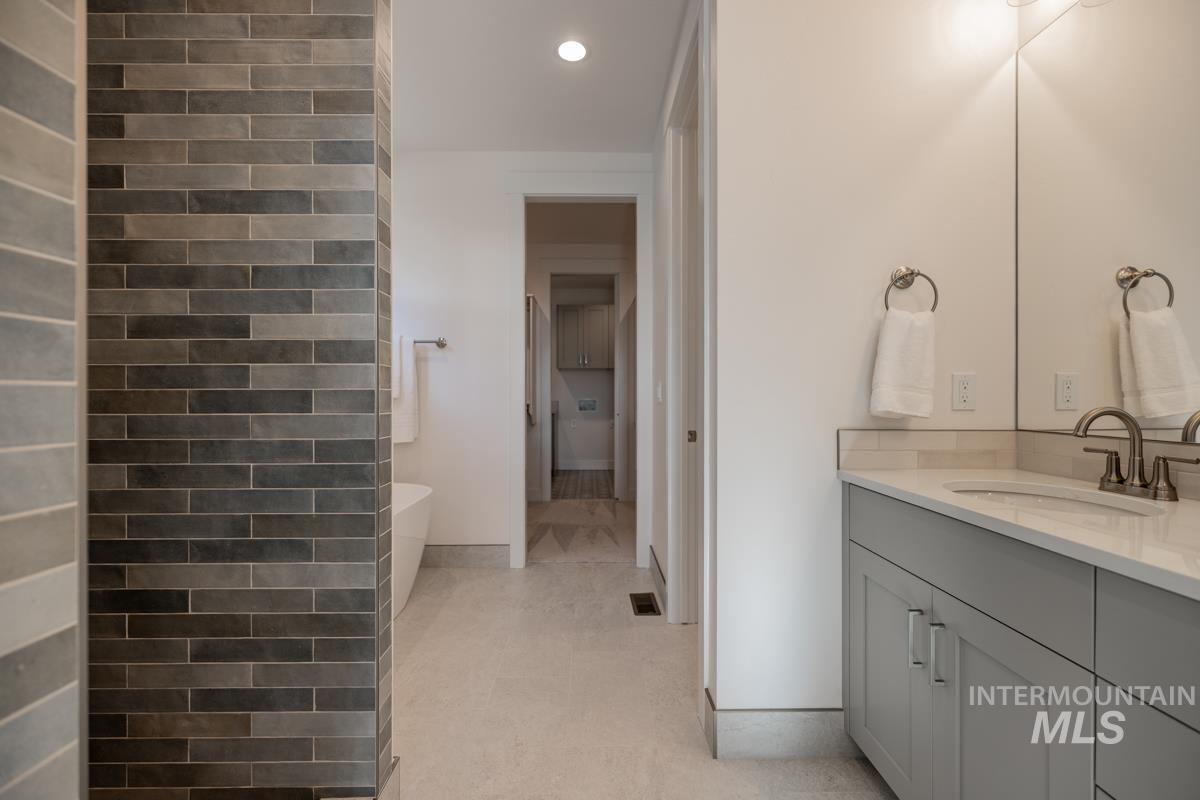 Bathroom featuring a soaking tub, vanity, and recessed lighting