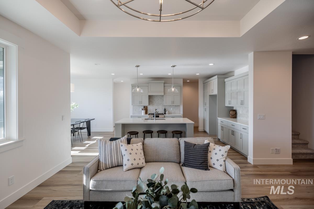 Living area featuring a chandelier, light wood-style floors, a raised ceiling, and recessed lighting