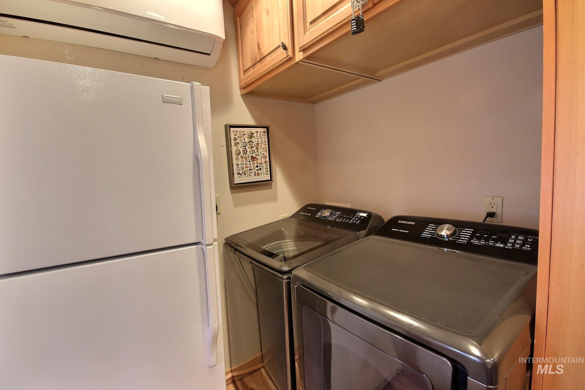 Laundry room with a wall mounted air conditioner and washing machine and clothes dryer