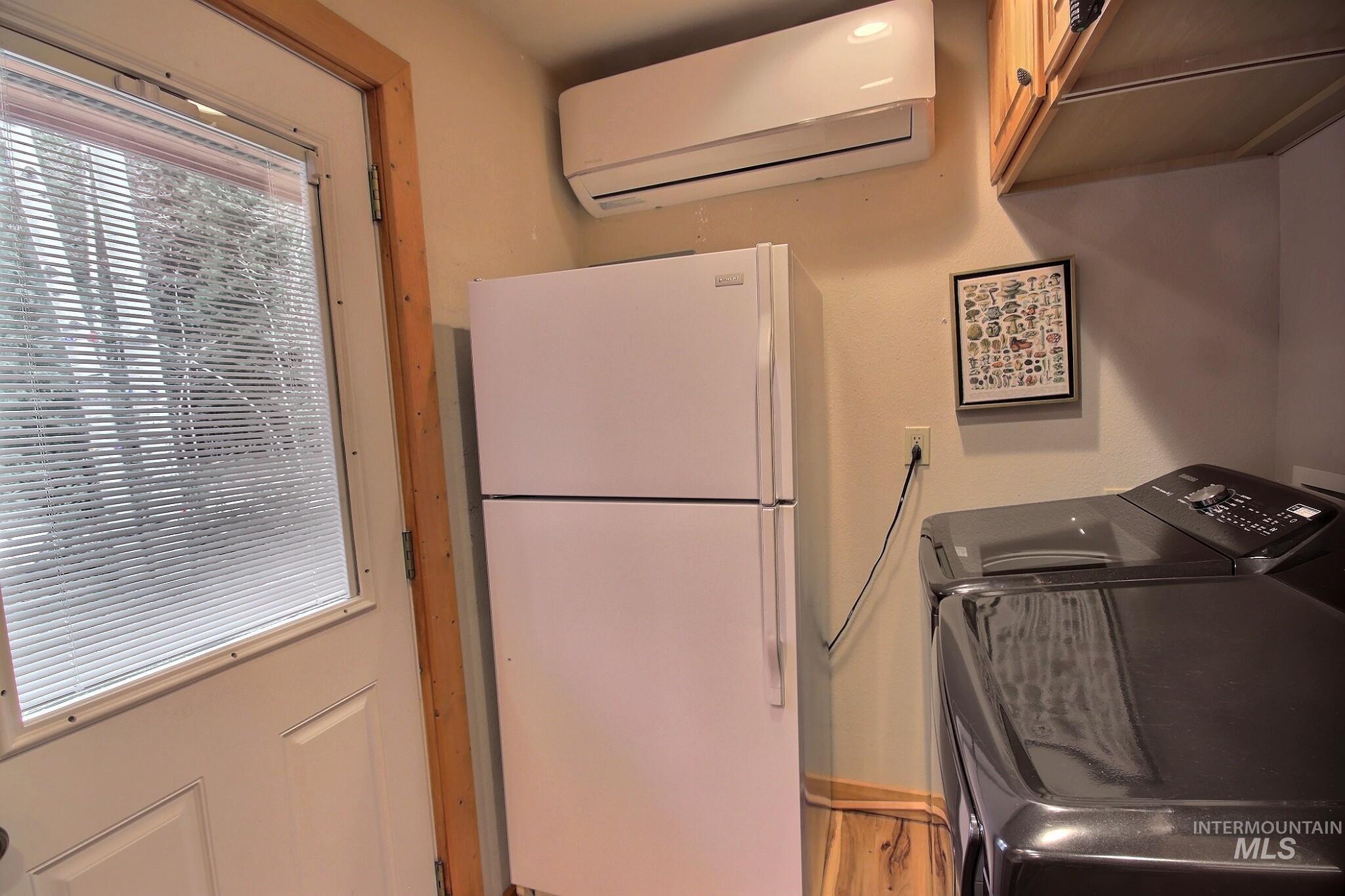 Washroom featuring a wall unit AC and washer and dryer