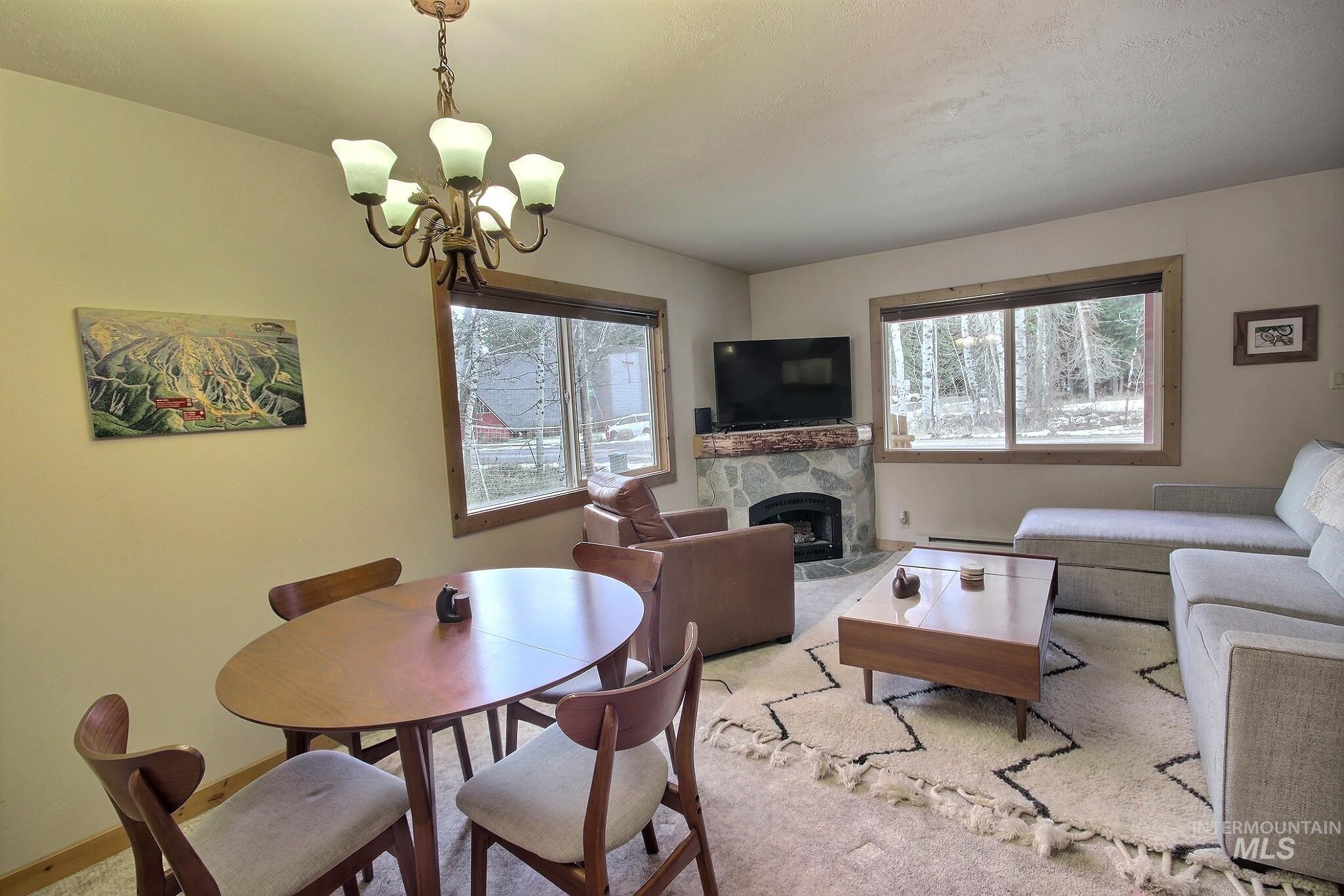 Dining space with a fireplace, healthy amount of natural light, a chandelier, and baseboard heating