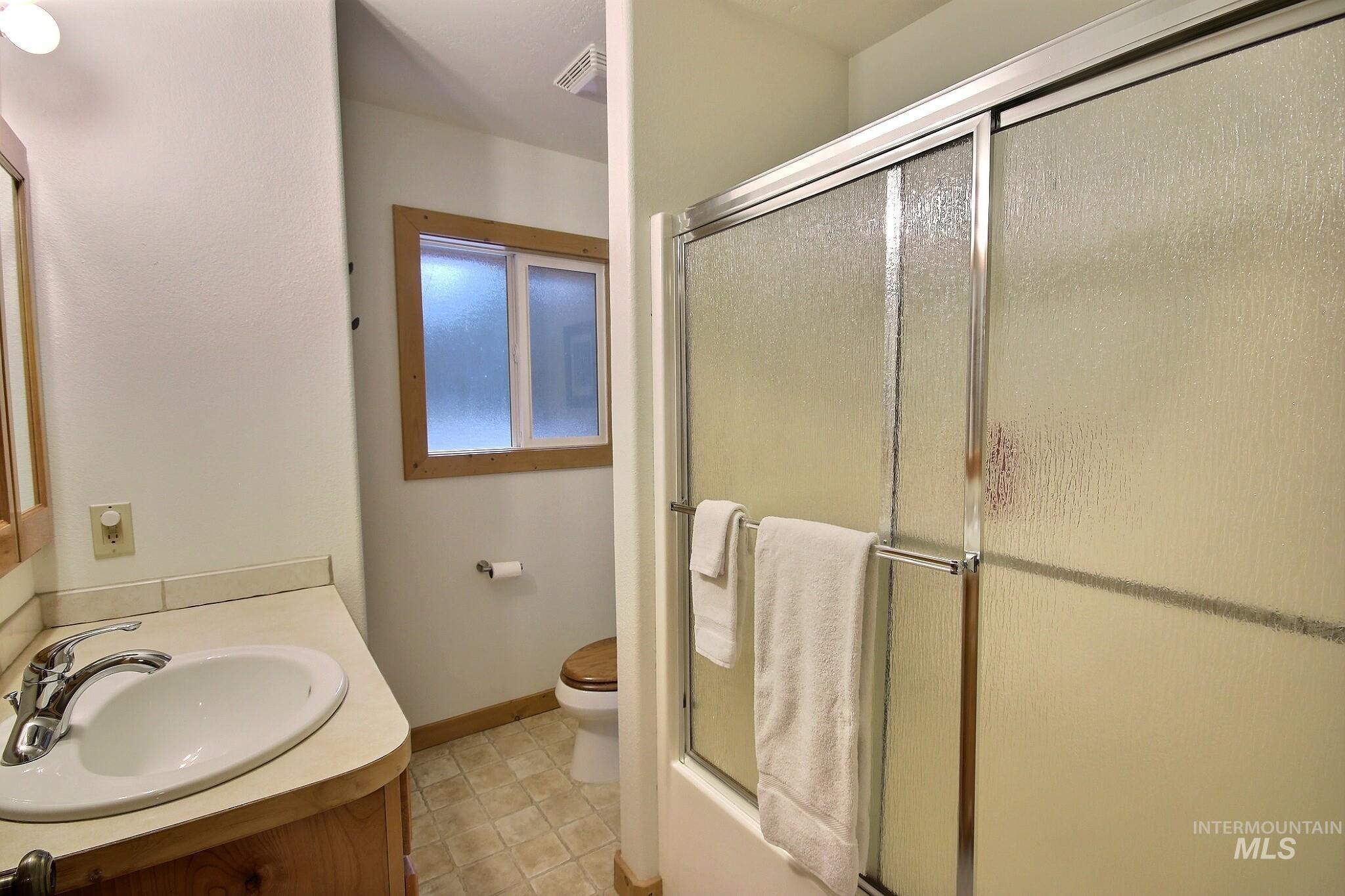 Full bathroom featuring vanity, light tile patterned floors, and enclosed tub / shower combo