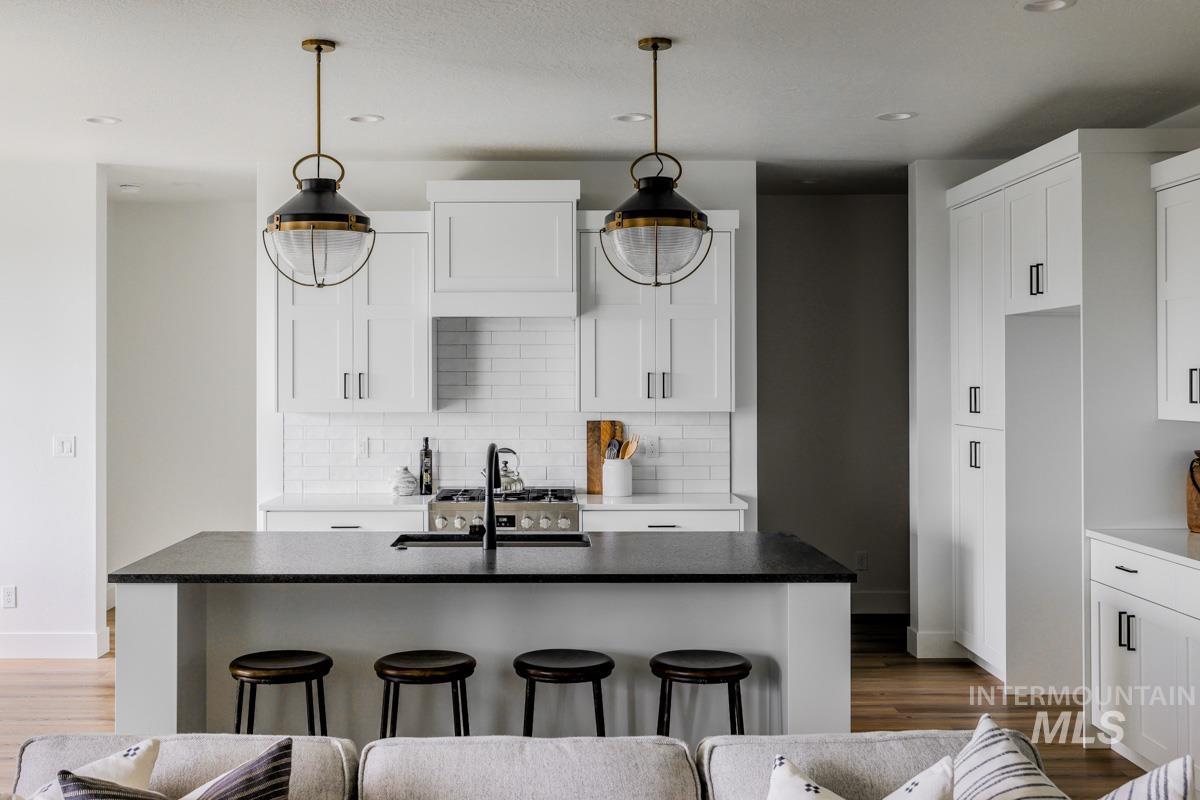 Kitchen with a kitchen island with sink, a kitchen breakfast bar, decorative light fixtures, white cabinetry, and recessed lighting