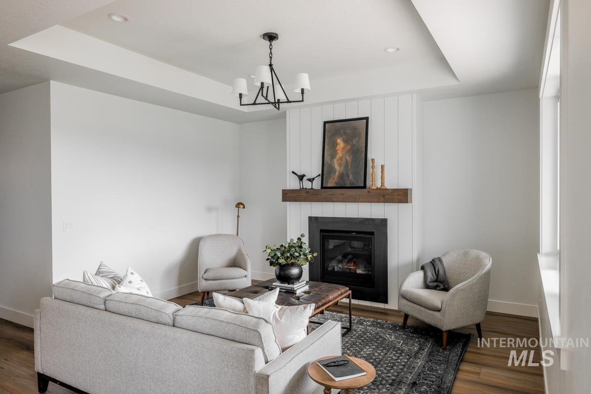 Living room with a tray ceiling, a fireplace, dark wood-type flooring, and recessed lighting