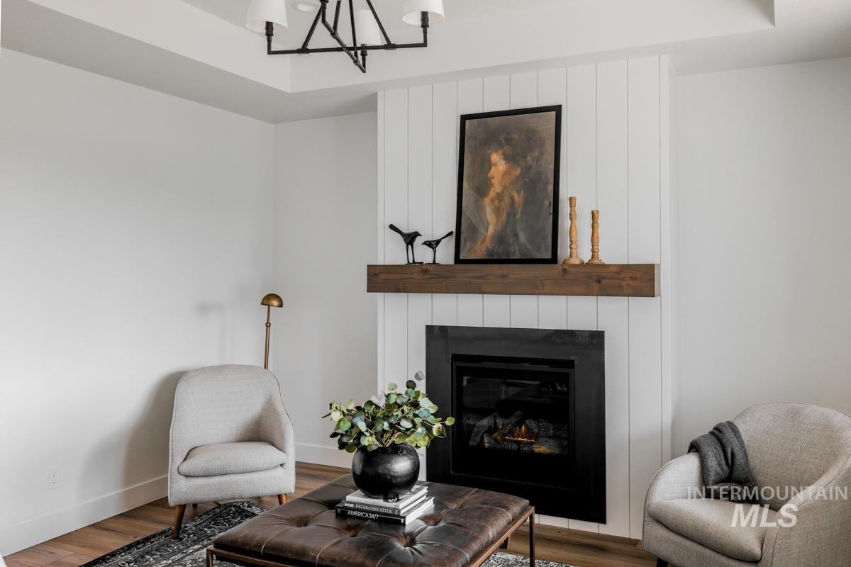 Sitting room with a large fireplace, wood finished floors, and a chandelier