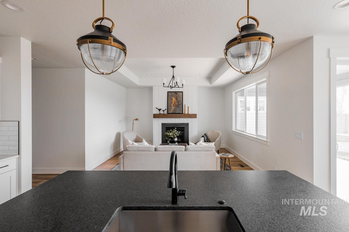 Kitchen featuring open floor plan, dark stone counters, wood finished floors, and a fireplace