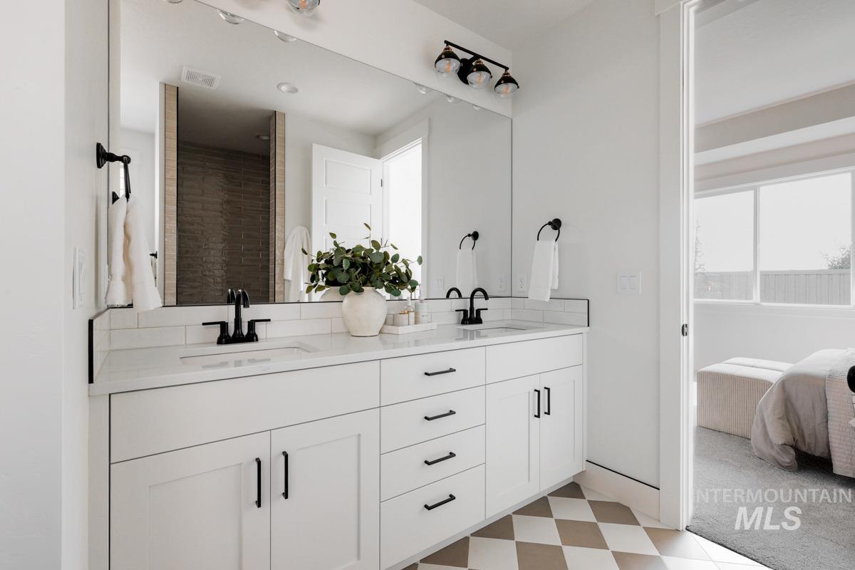 Ensuite bathroom with light floors, double vanity, and a shower