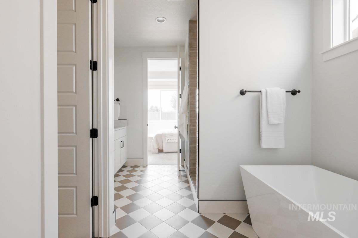 Bathroom featuring a freestanding tub, ensuite bath, vanity, and light flooring