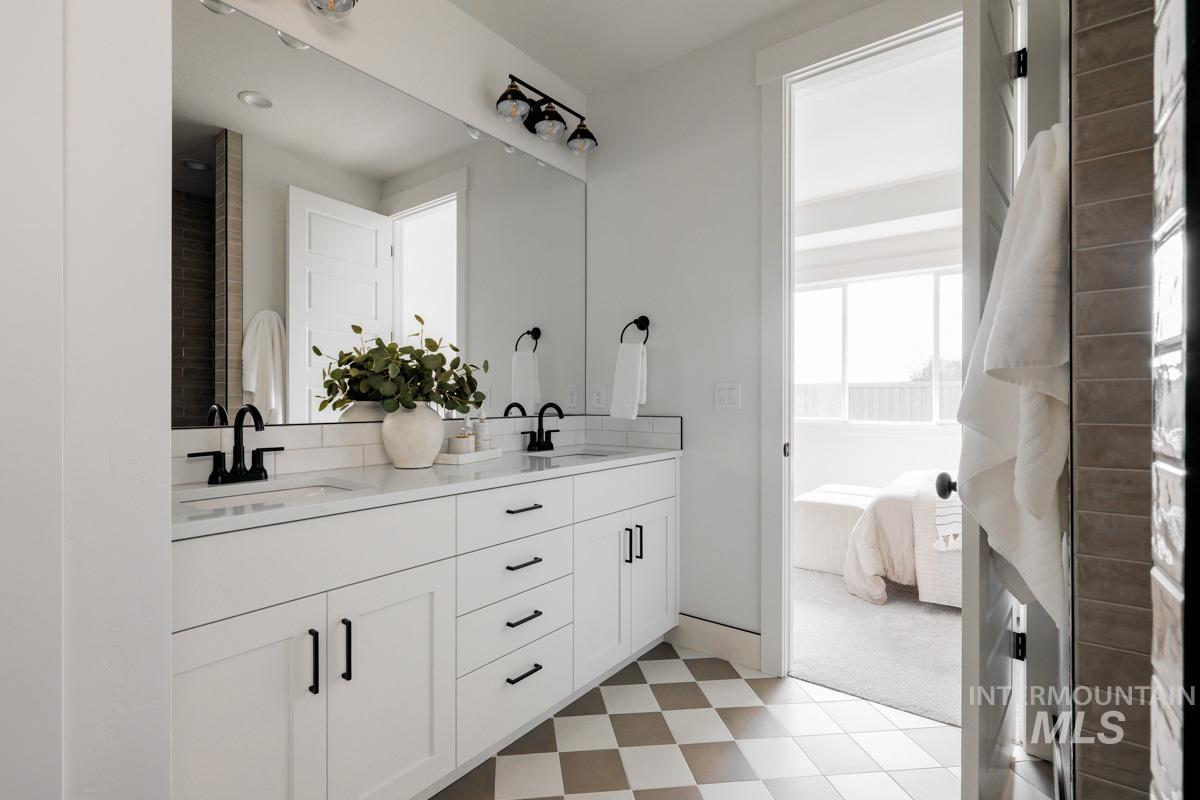 Ensuite bathroom featuring double vanity and light floors