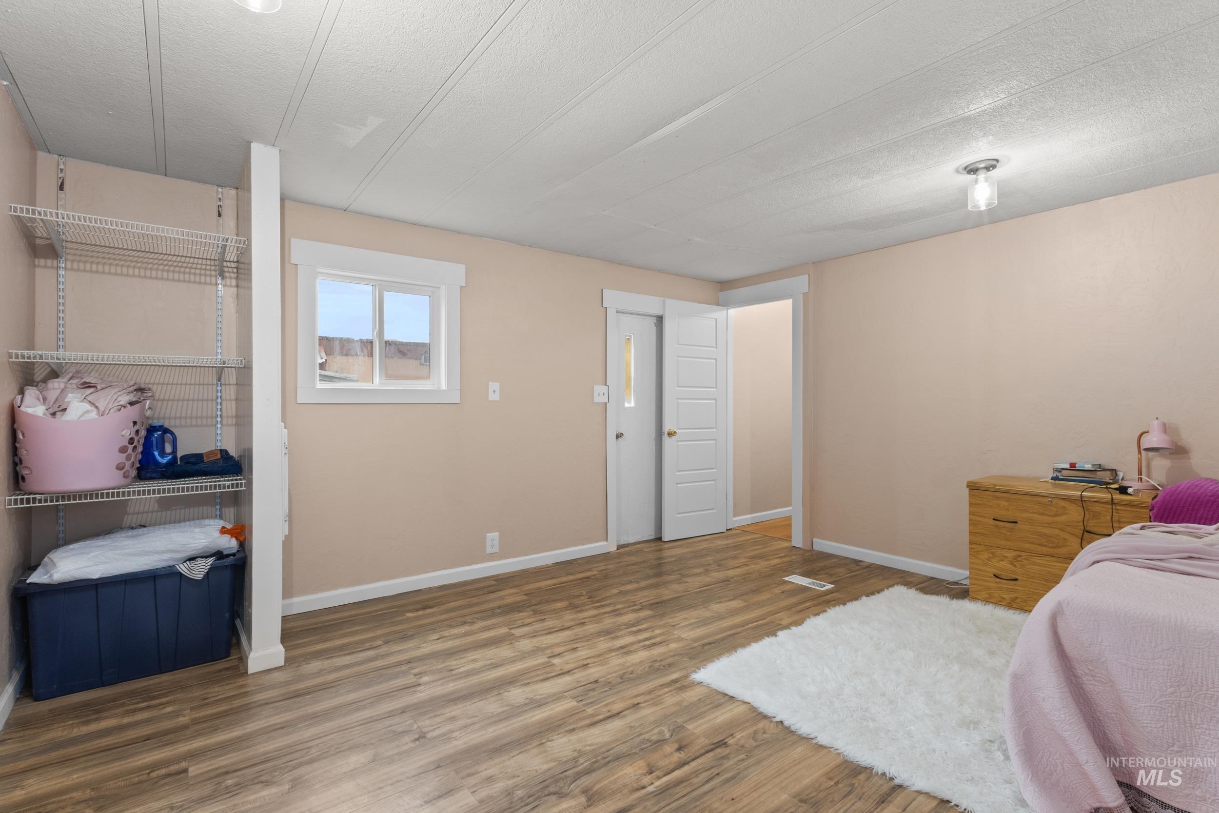 Bedroom with wood finished floors and a textured ceiling