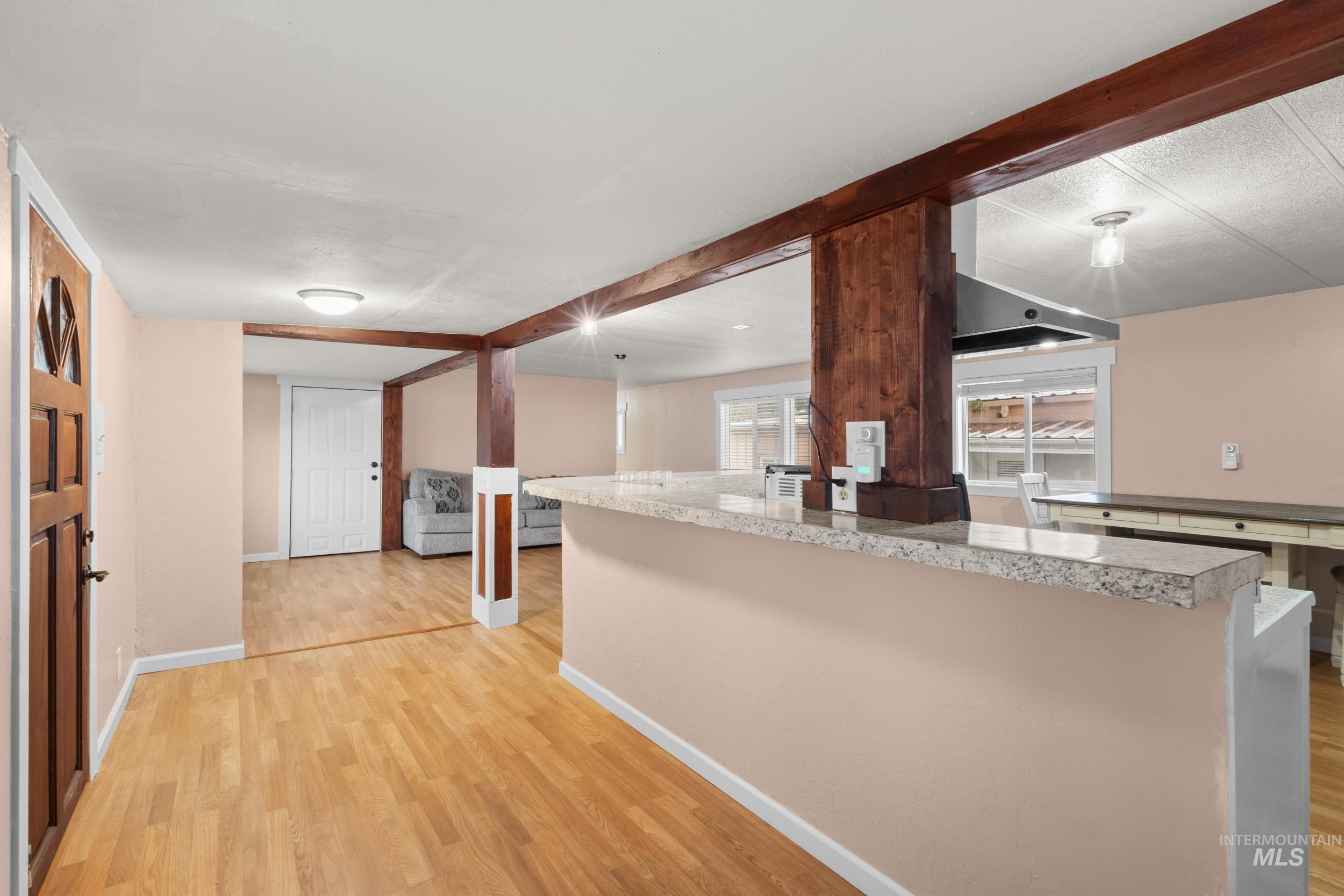 Kitchen with light countertops, light wood-style flooring, and beam ceiling