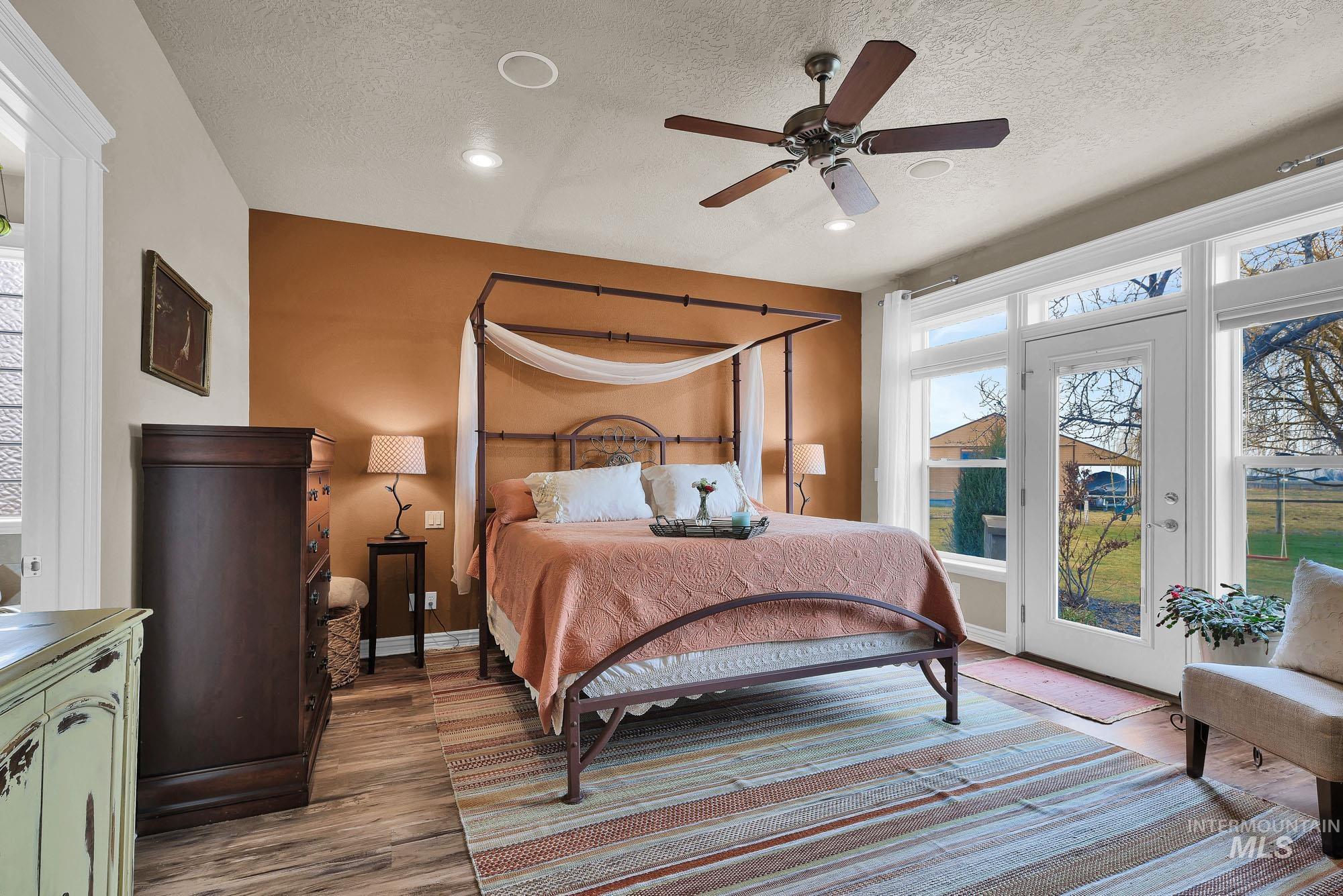 Bedroom featuring ceiling fan, access to back patio and hot tub, engineered wood finished floors, and a textured ceiling