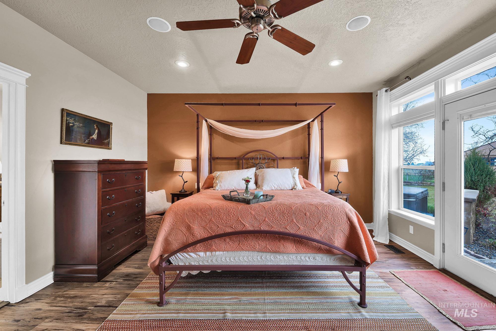 Bedroom featuring plentiful windows with access to the patio and hot tub, engineered wood finished floors, ceiling fan, recessed lighting, and a corner Gas fireplace