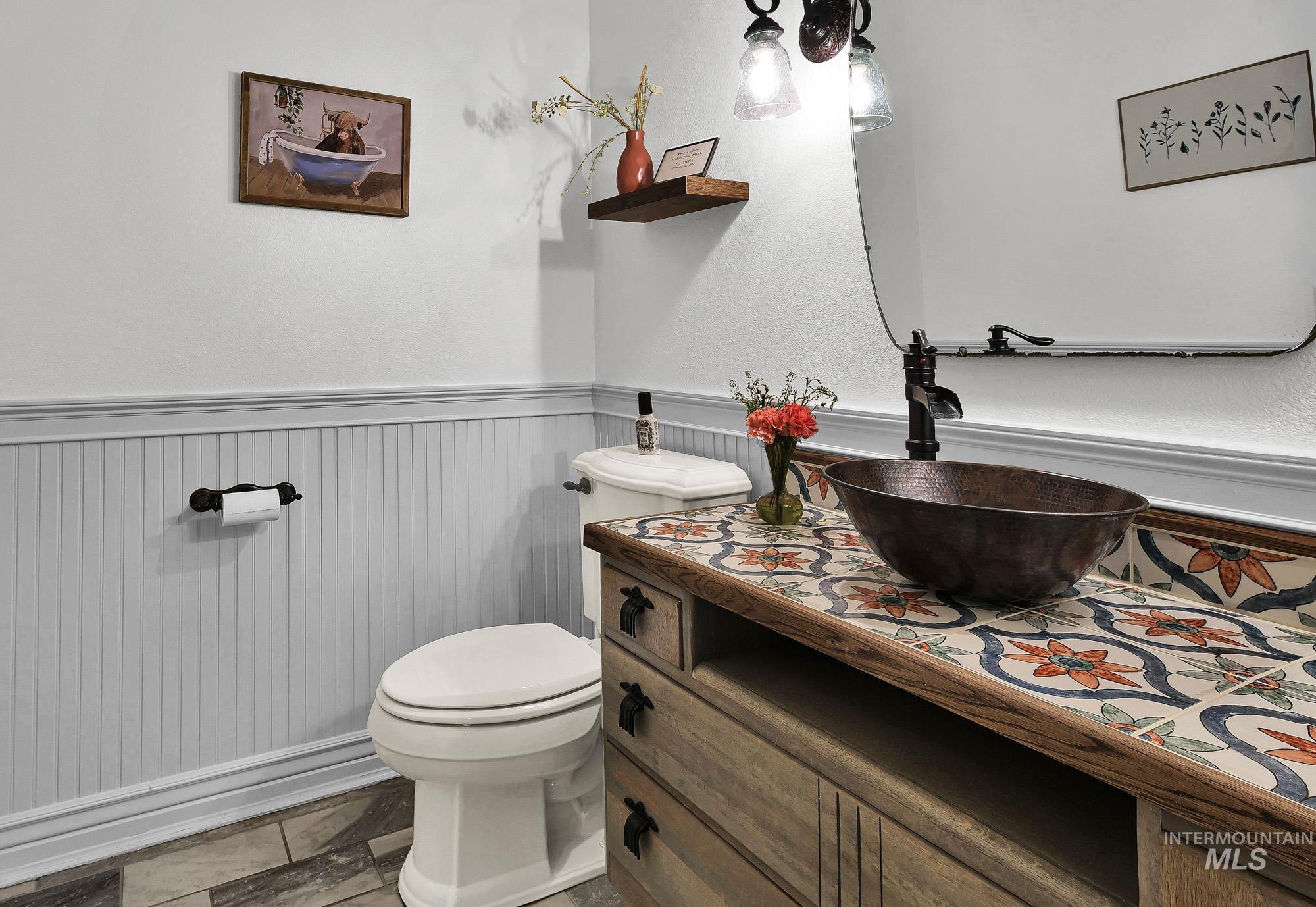 Half bath with a wainscoted wall and vanity