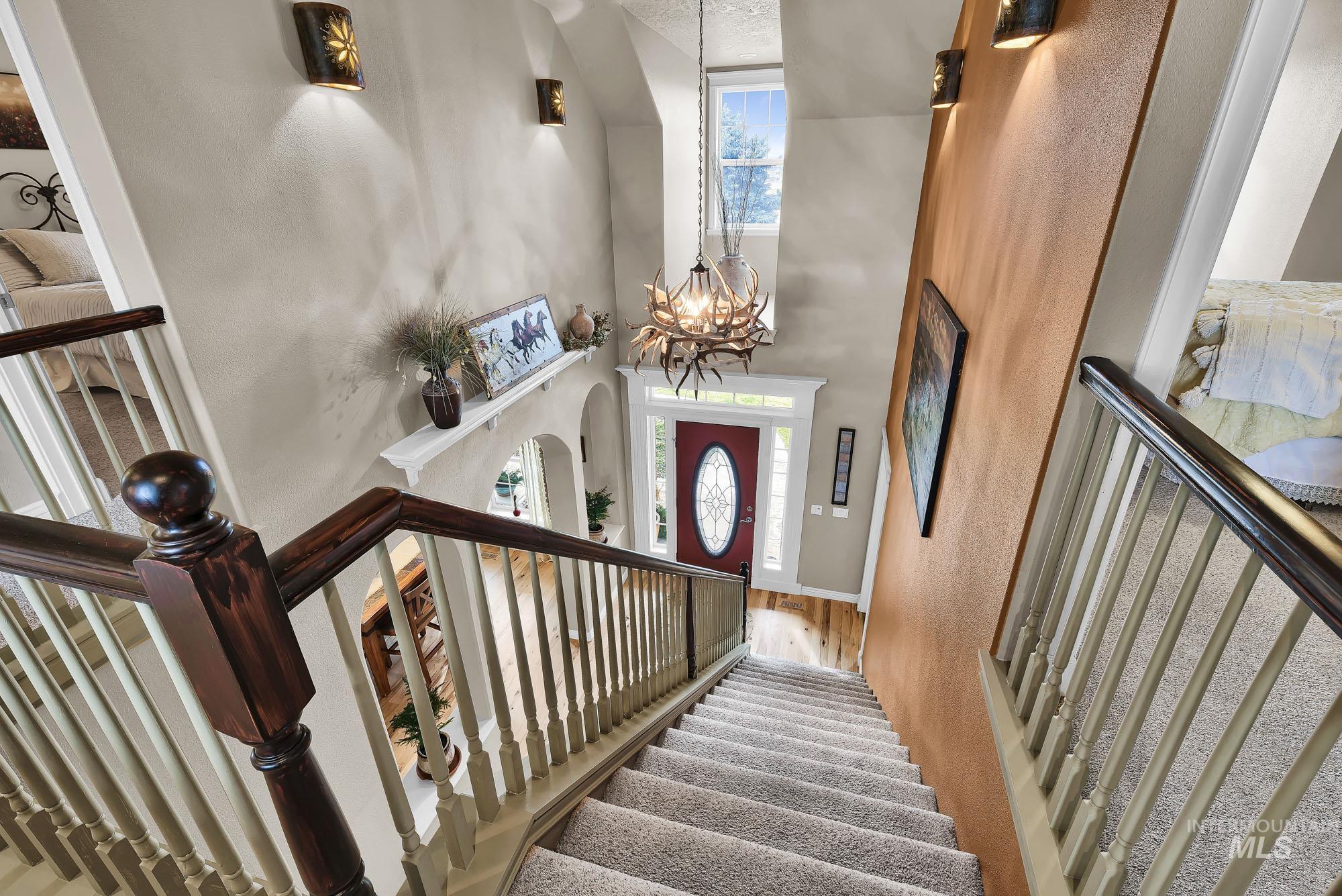 Foyer featuring a unique antler chandelier, a towering 2 story ceiling, stairs, arched walkways, and Maple re-finished floors