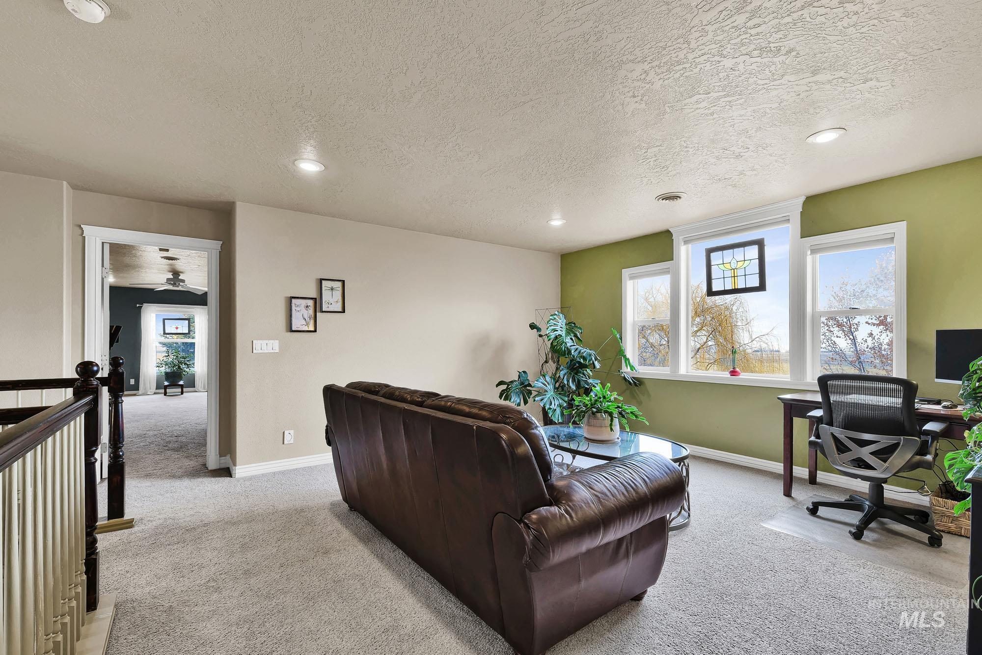 Living area with a desk, light colored carpet, a textured ceiling, and recessed lighting with views of the mountains