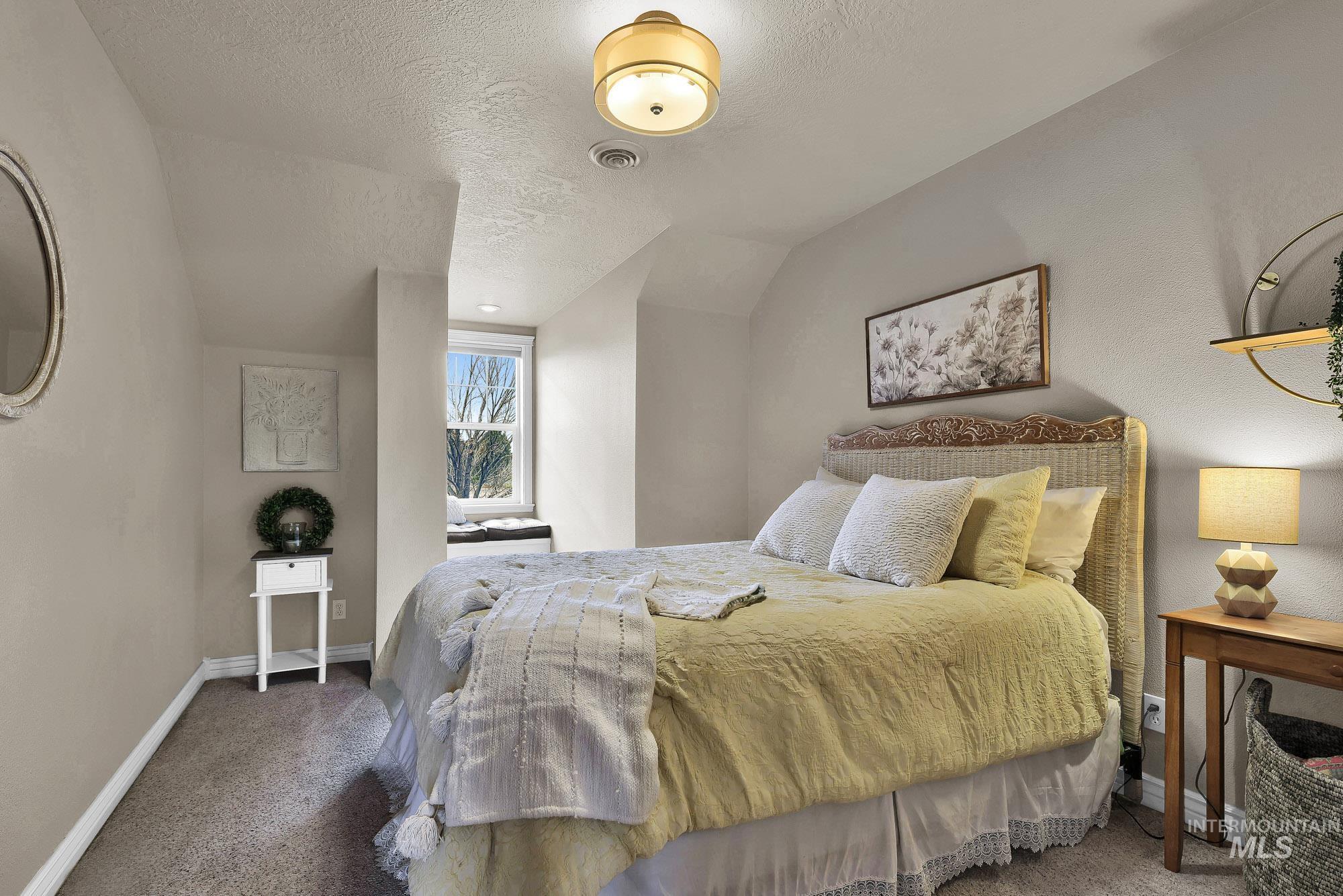 Bedroom with carpet floors, window seat and a textured ceiling