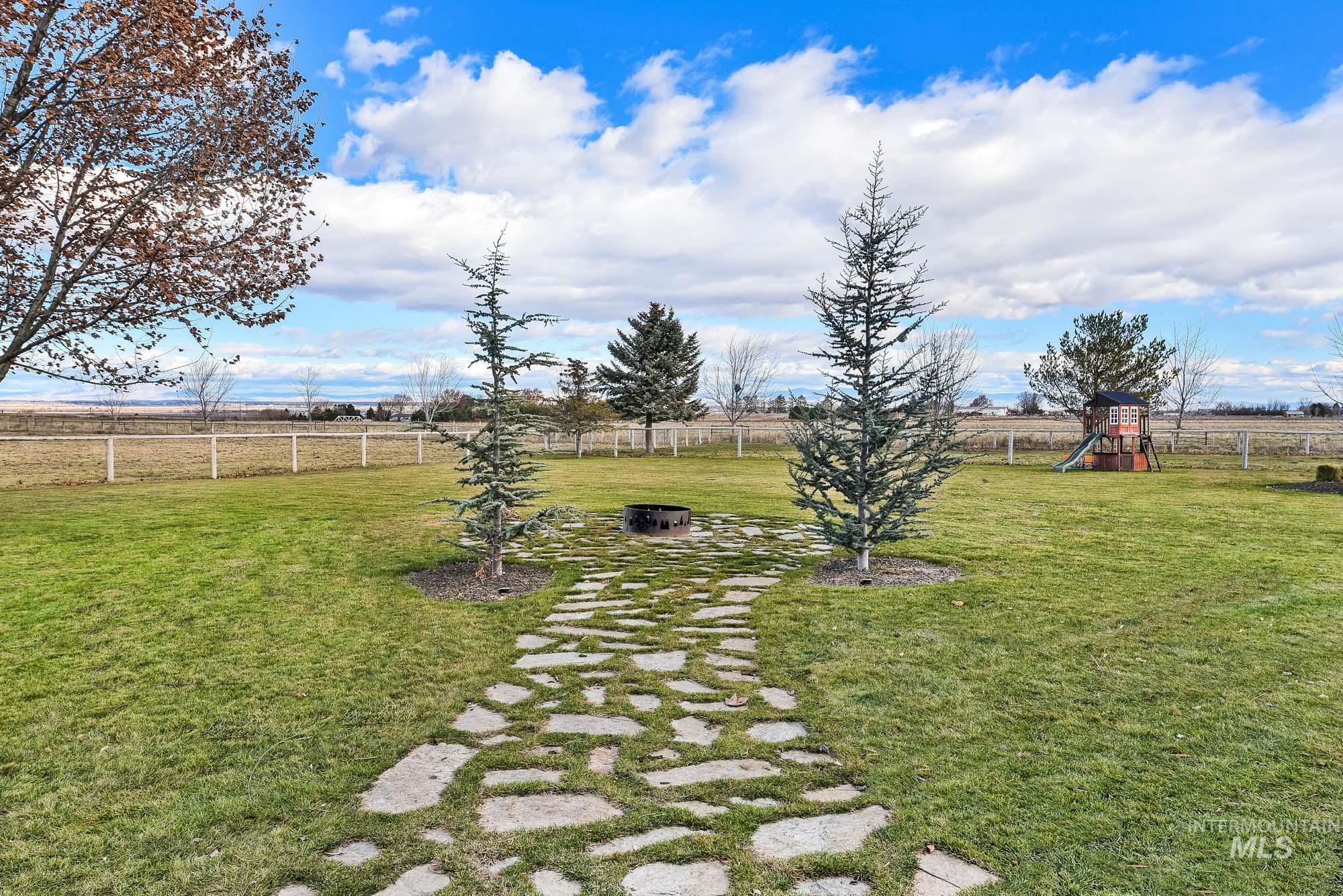View of yard featuring a rural view, a playground, and pavers to an outdoor fire pit