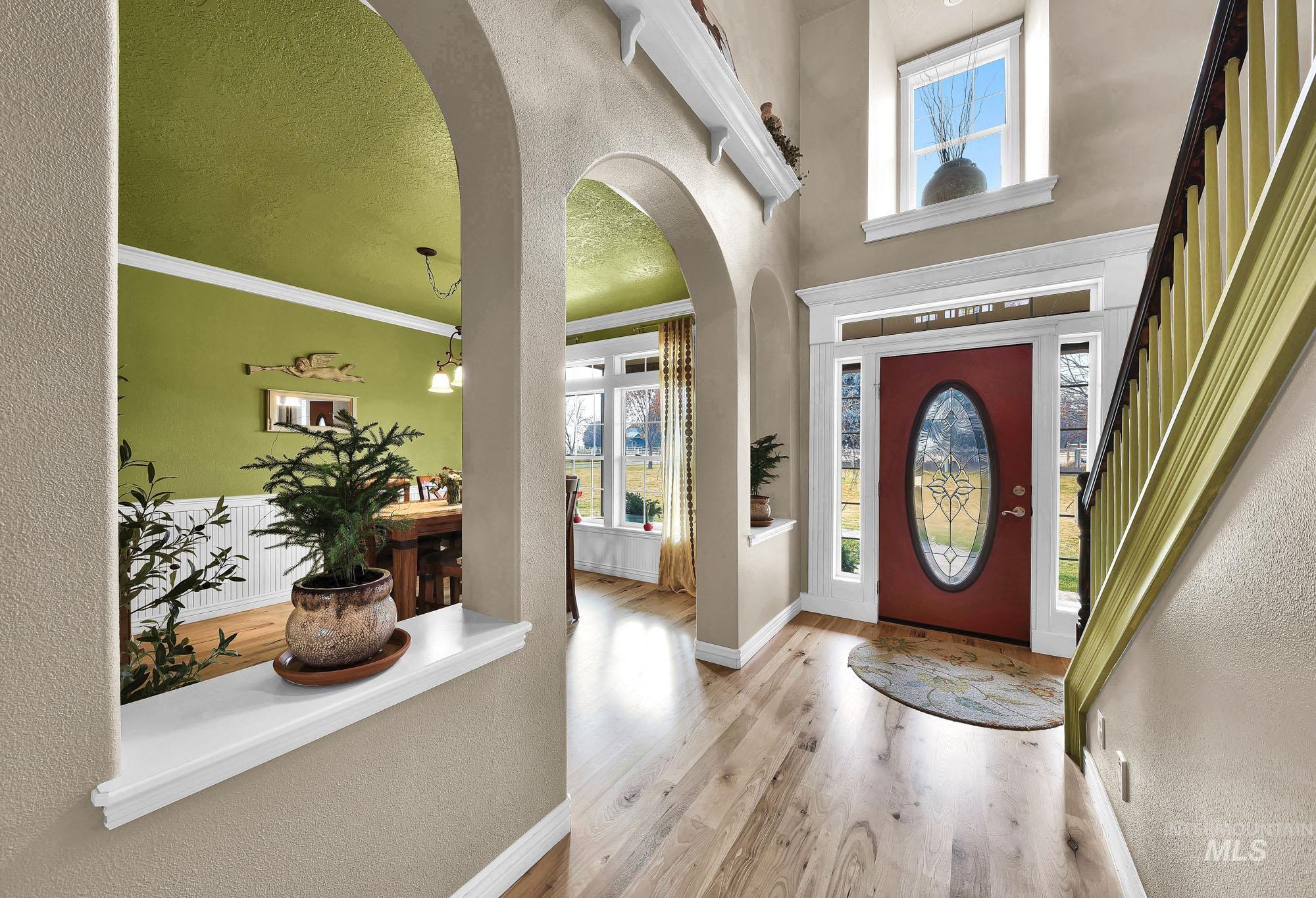 Foyer entrance featuring arched walkways, wood finished floors, a textured wall, ornamental molding, and a chandelier