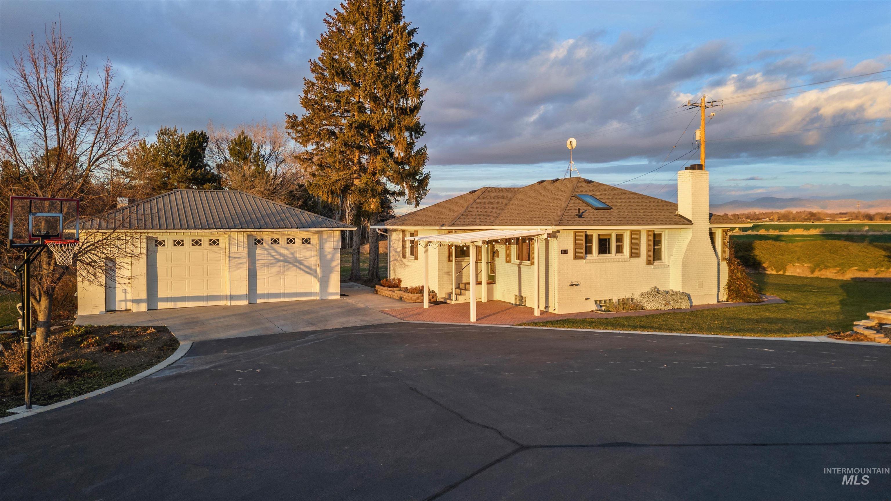 Single story home featuring an outdoor structure, a chimney, a detached garage, a front yard, and brick siding