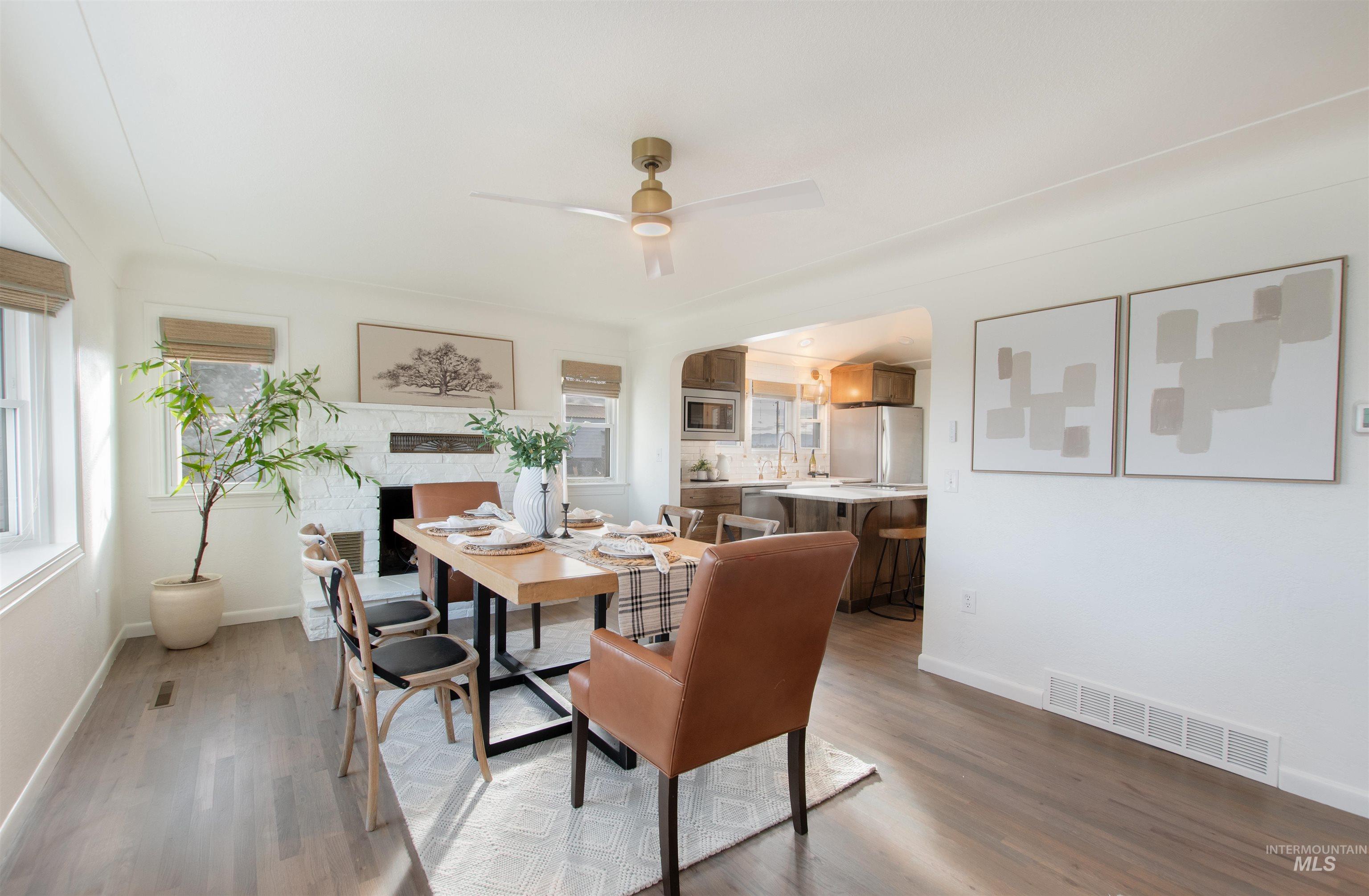 Dining space with light wood-style floors, ceiling fan, and a fireplace