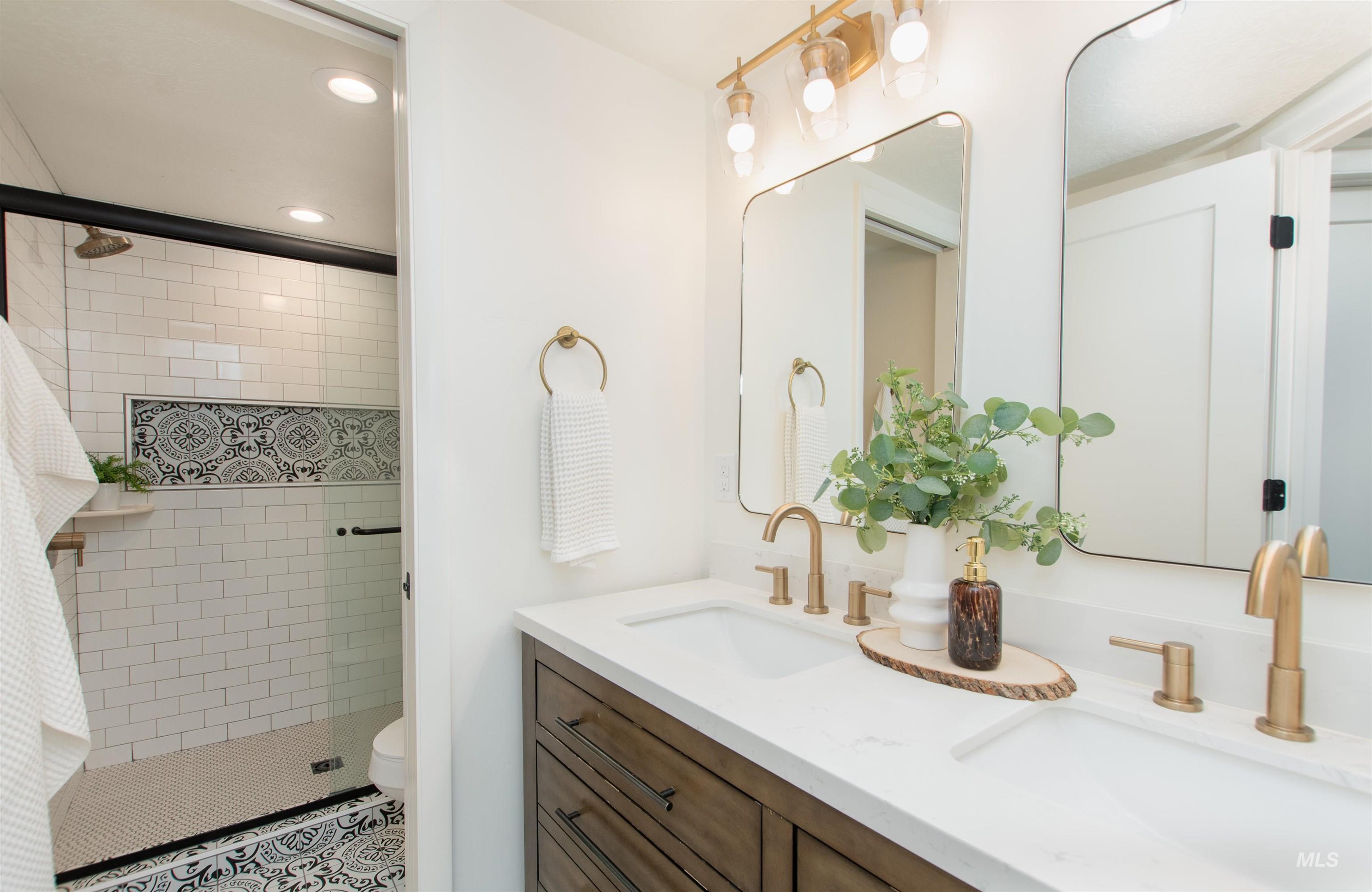 Full bathroom with double vanity, recessed lighting, and a stall shower