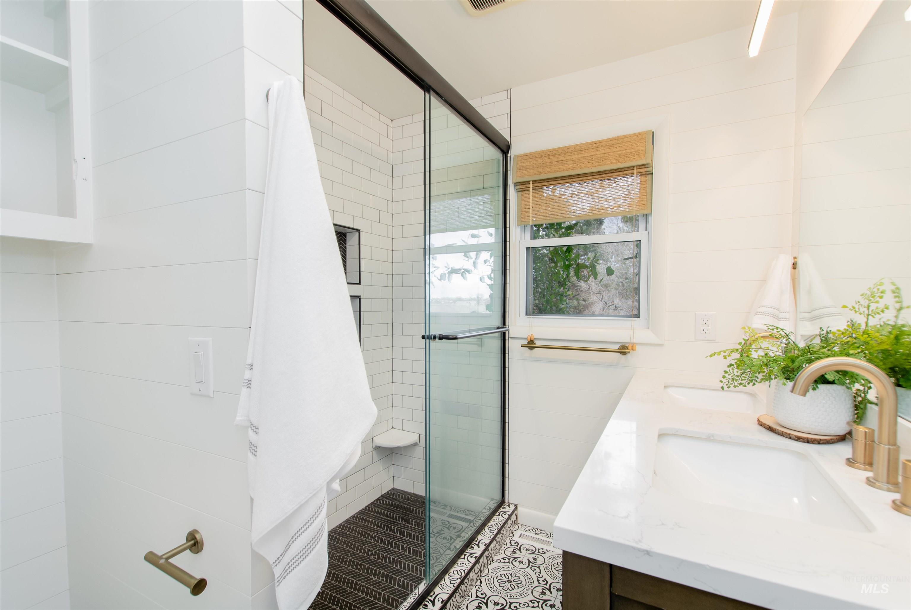 Full bathroom with double vanity and a shower stall