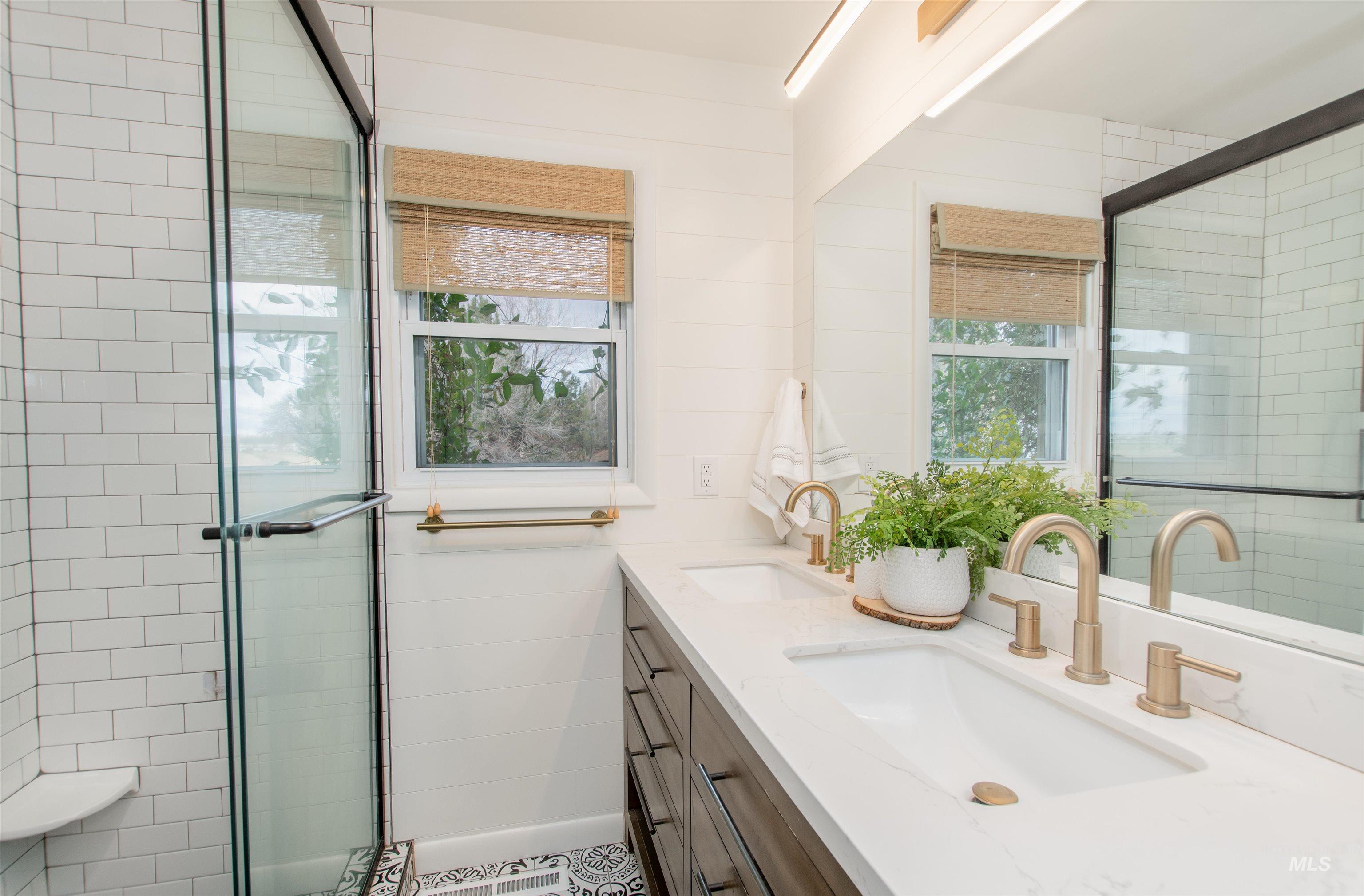 Full bathroom featuring double vanity, a stall shower, and healthy amount of natural light