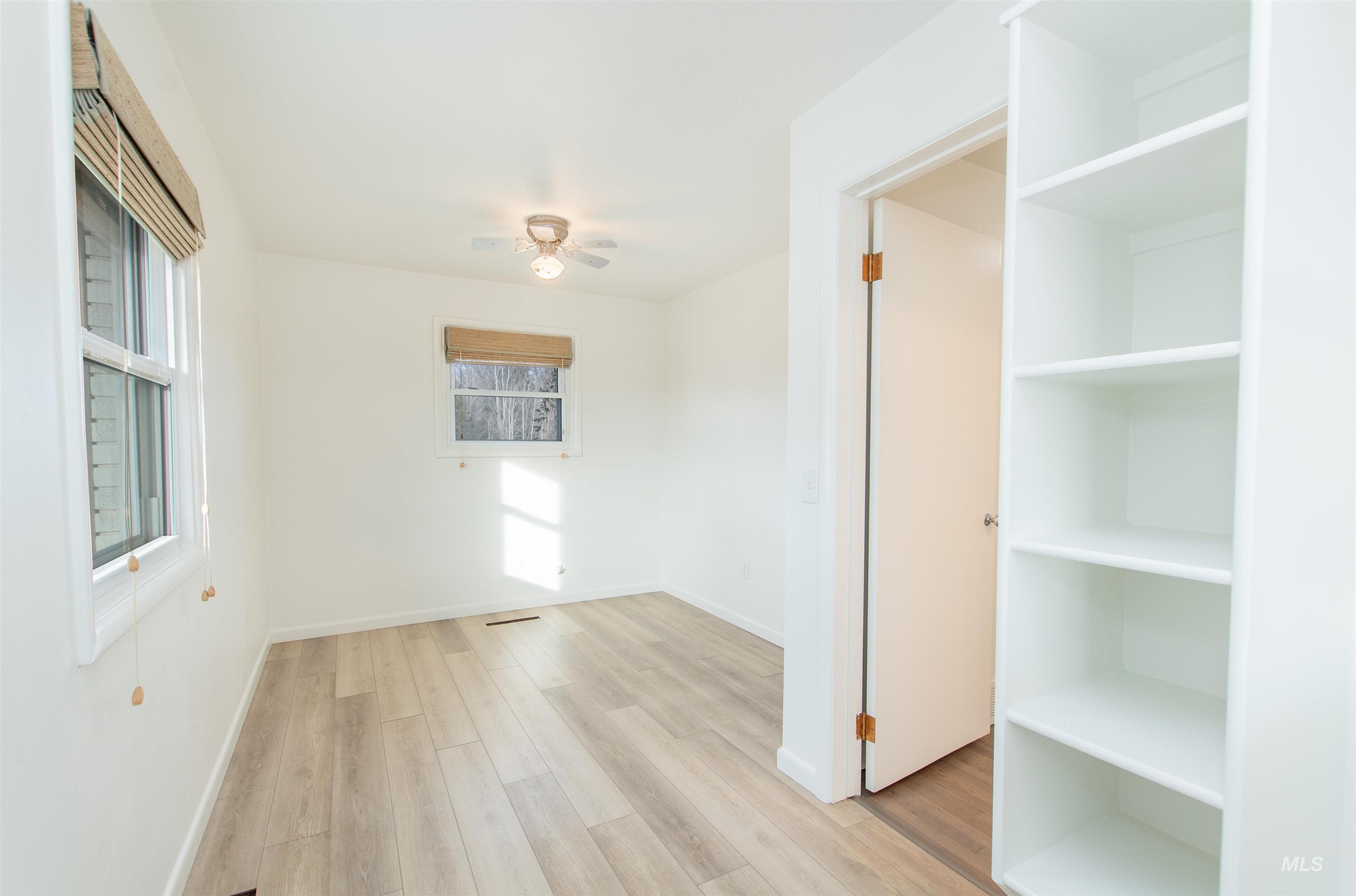 Empty room with light wood-style floors and a ceiling fan