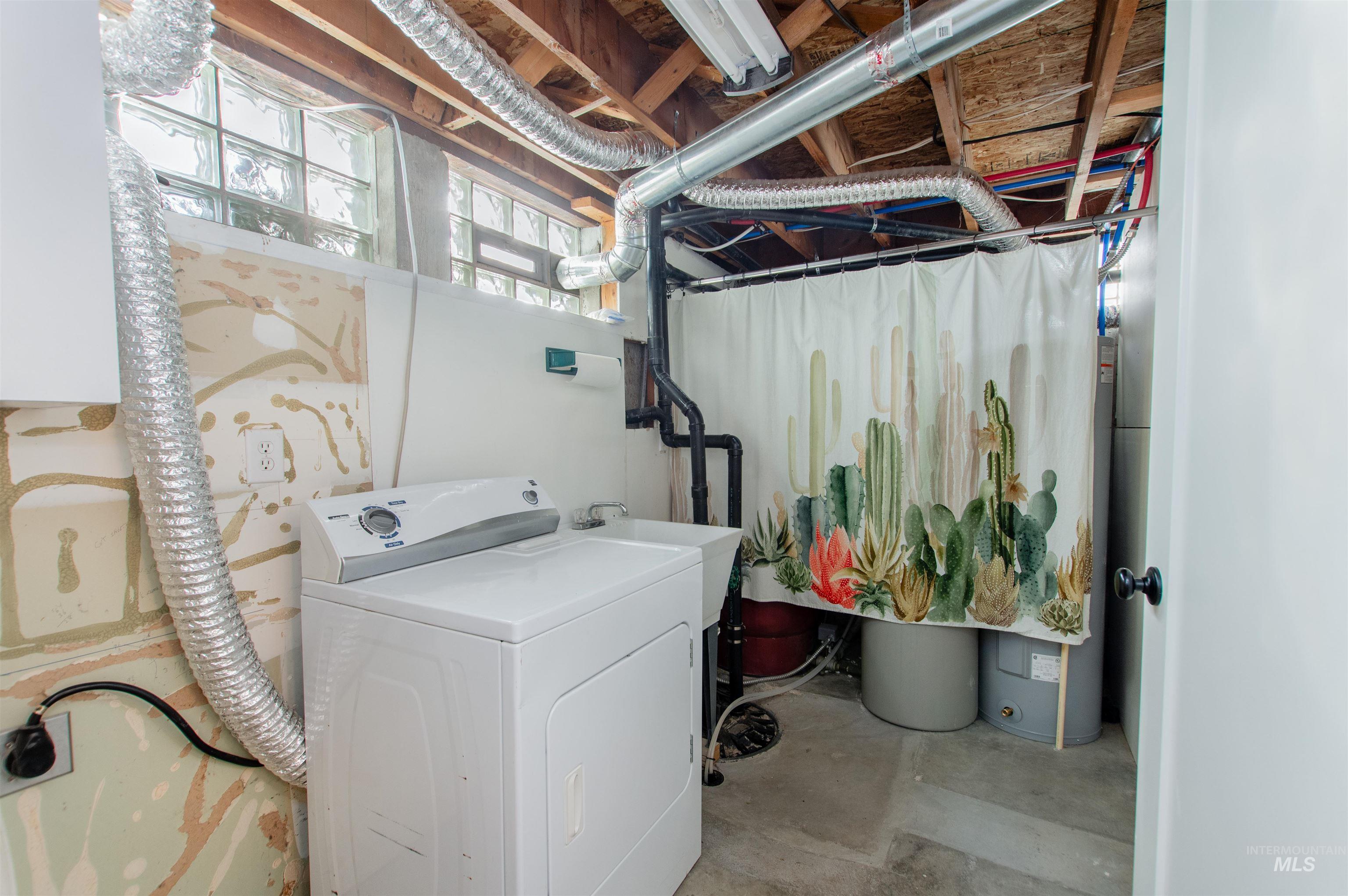 Washroom with washer / dryer, unfinished concrete floors, and water heater