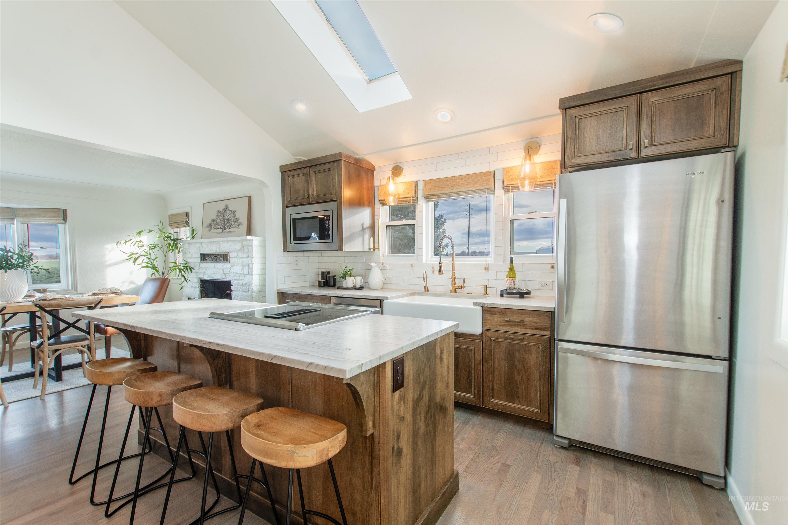 Kitchen with stainless steel appliances, a skylight, lofted ceiling, a breakfast bar area, and light wood finished floors