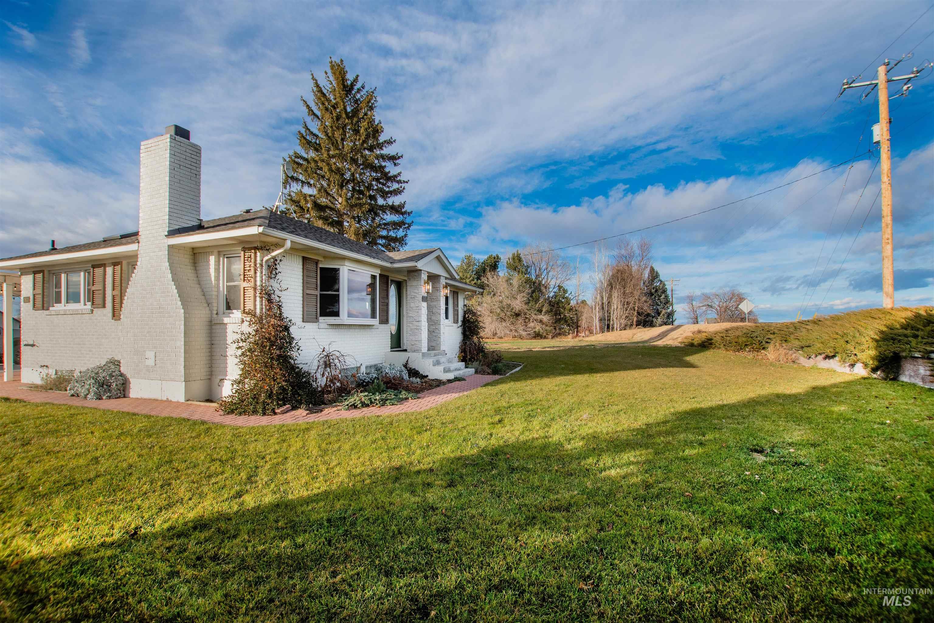 View of home's exterior with brick siding, a chimney, and a lawn