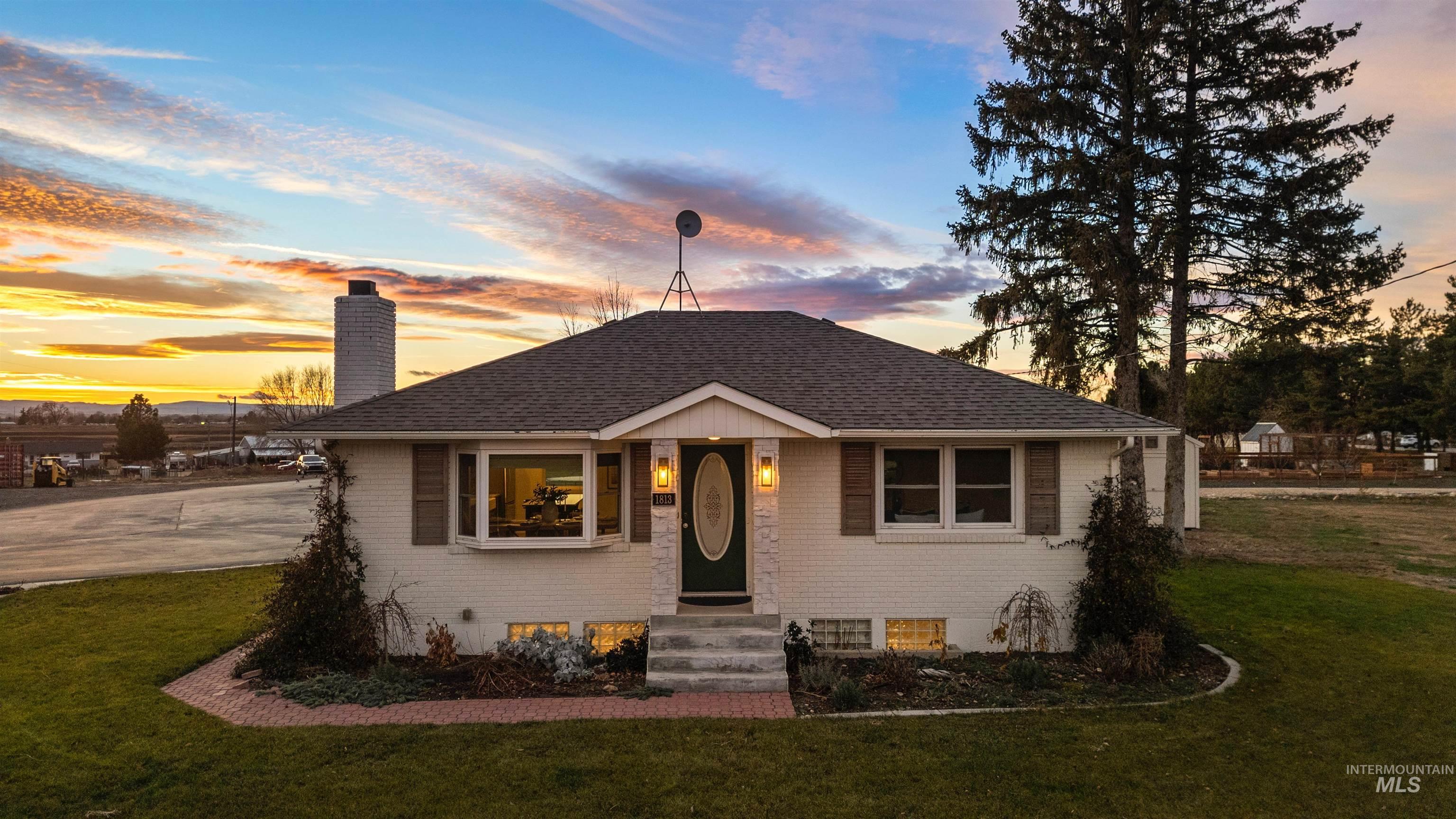Bungalow-style home with brick siding, a lawn, and a chimney