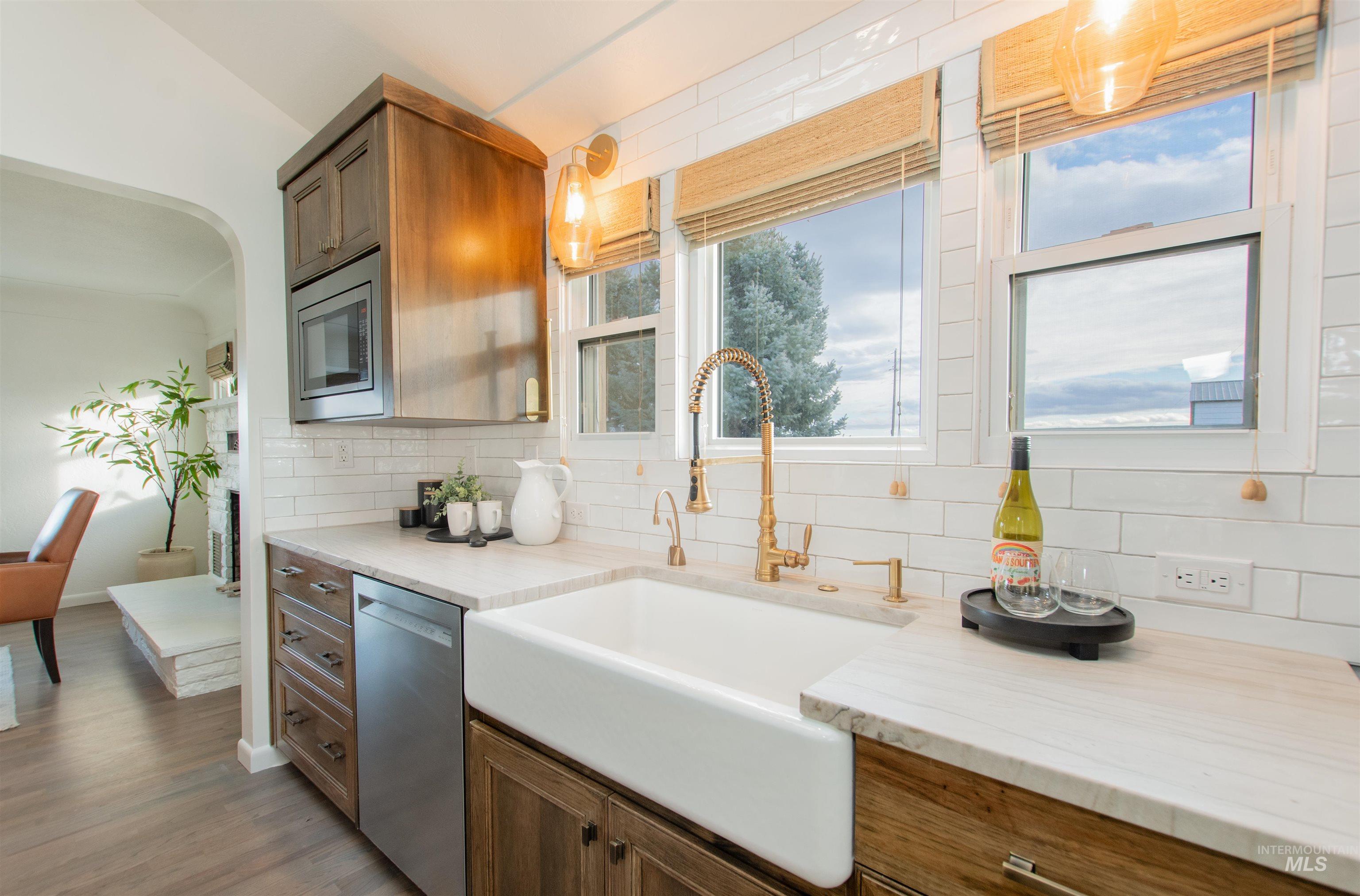 Kitchen featuring brown cabinetry, appliances with stainless steel finishes, decorative backsplash, and light wood-style floors