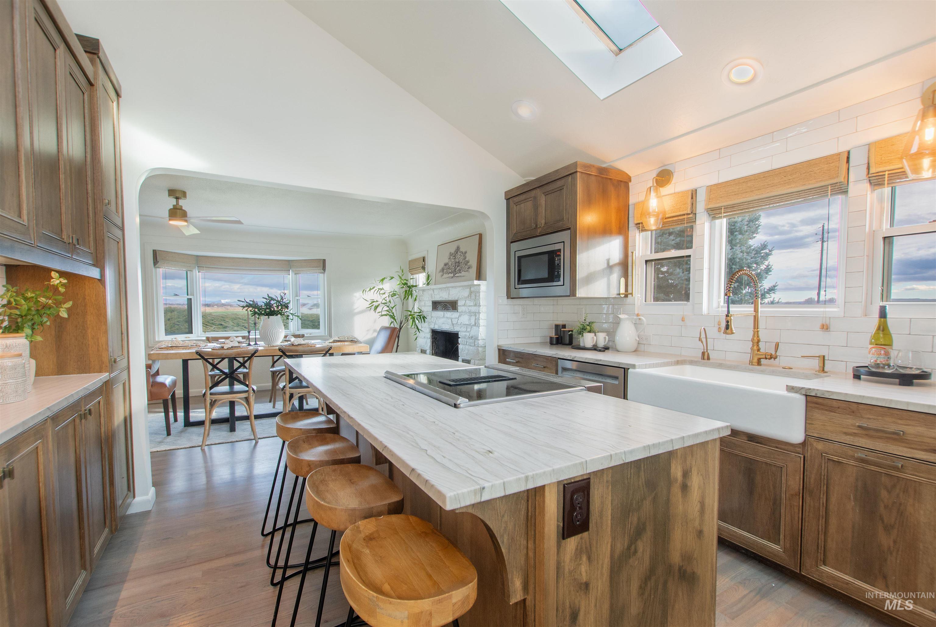 Kitchen featuring tasteful backsplash, brown cabinetry, vaulted ceiling, a kitchen island, and a skylight
