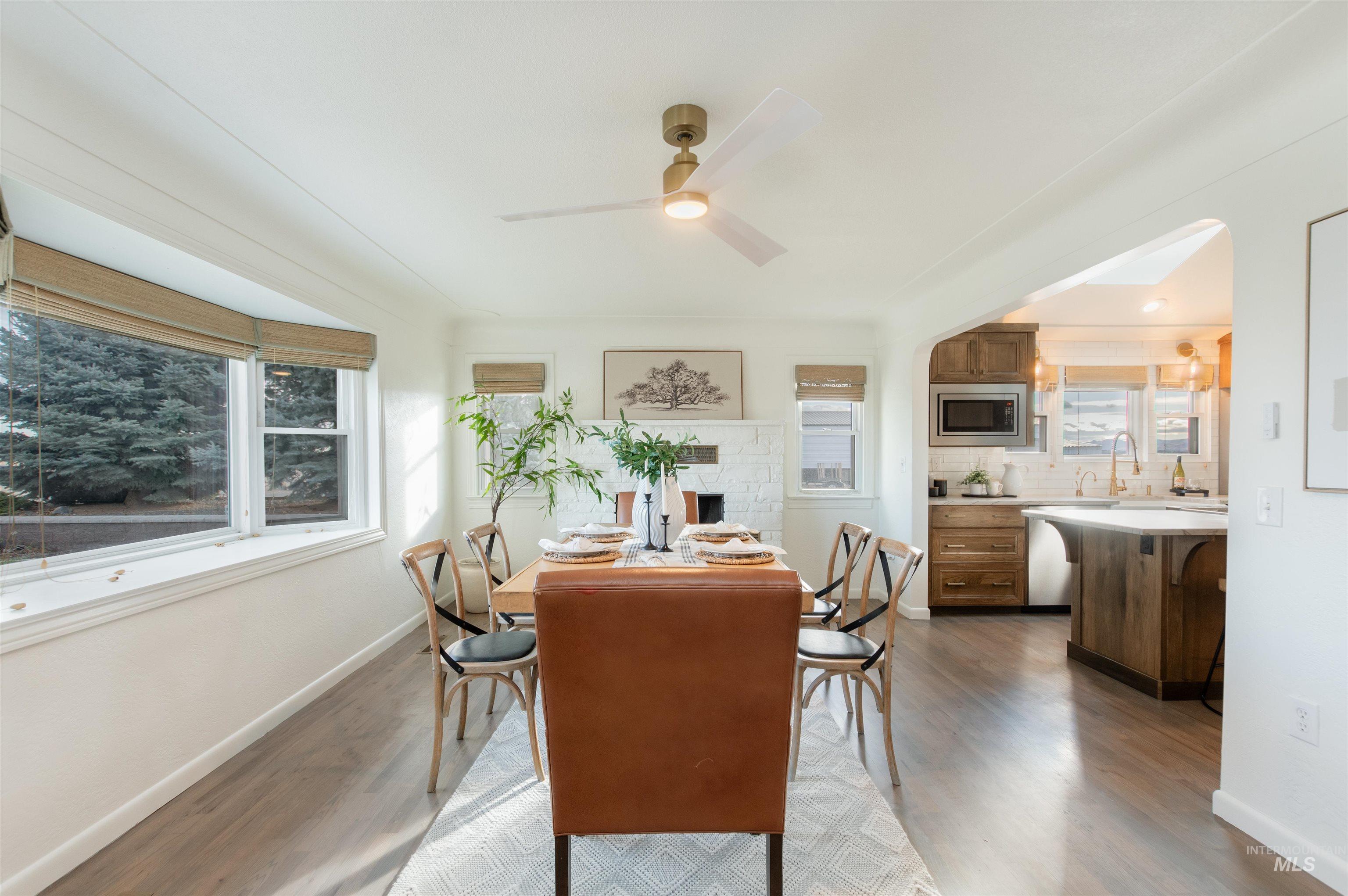 Dining room with light wood-style floors, a ceiling fan, and a brick fireplace