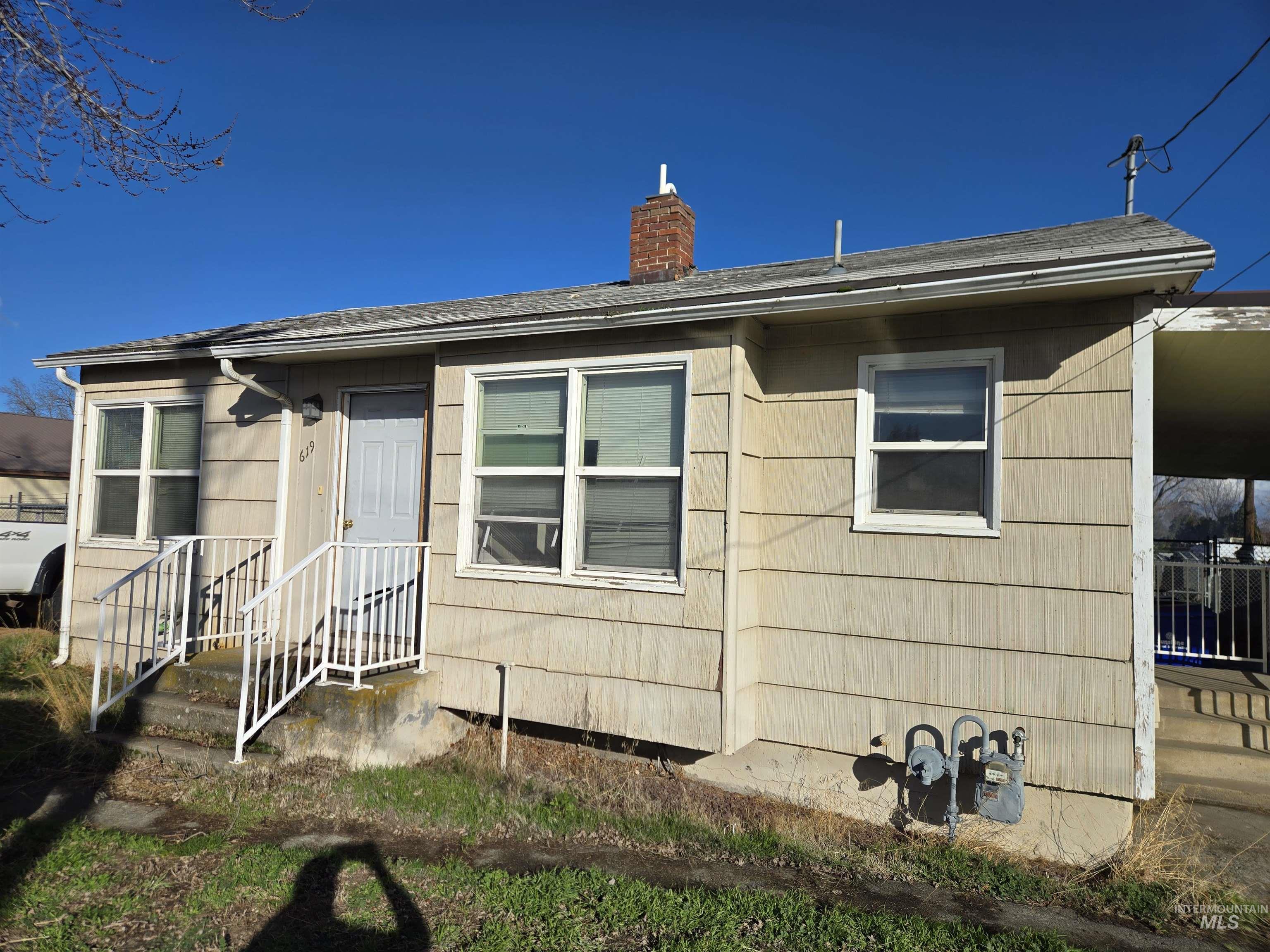 View of front of property with a chimney and oil tank
