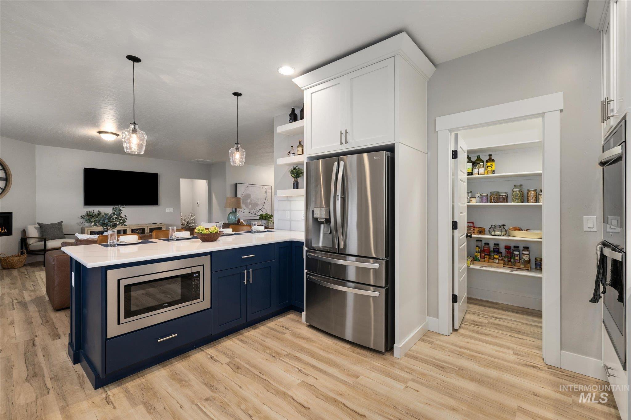 Kitchen featuring stainless steel appliances, a peninsula, open shelves, open floor plan, and decorative light fixtures