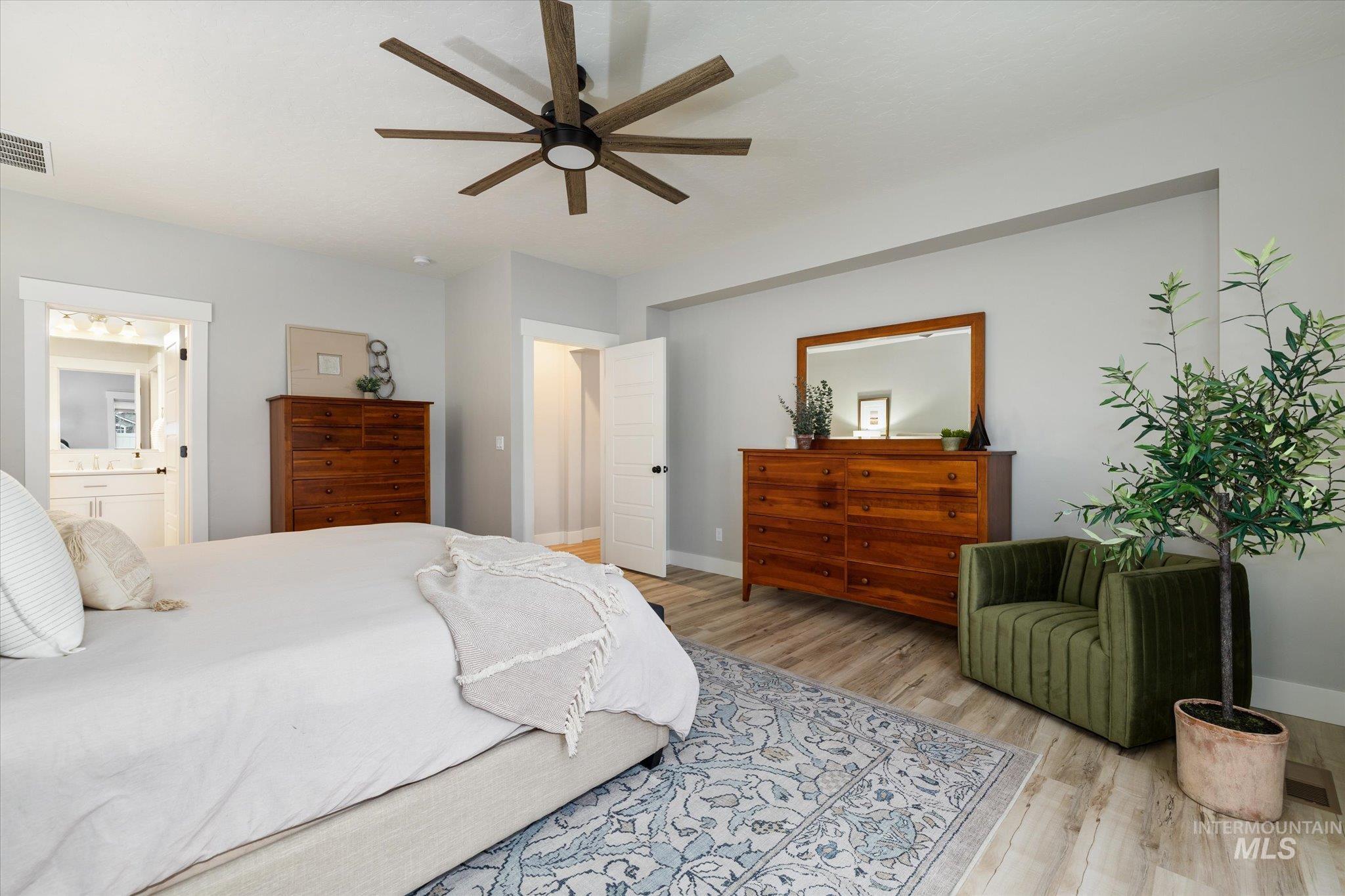 Bedroom with ceiling fan, wood finished floors, and ensuite bath