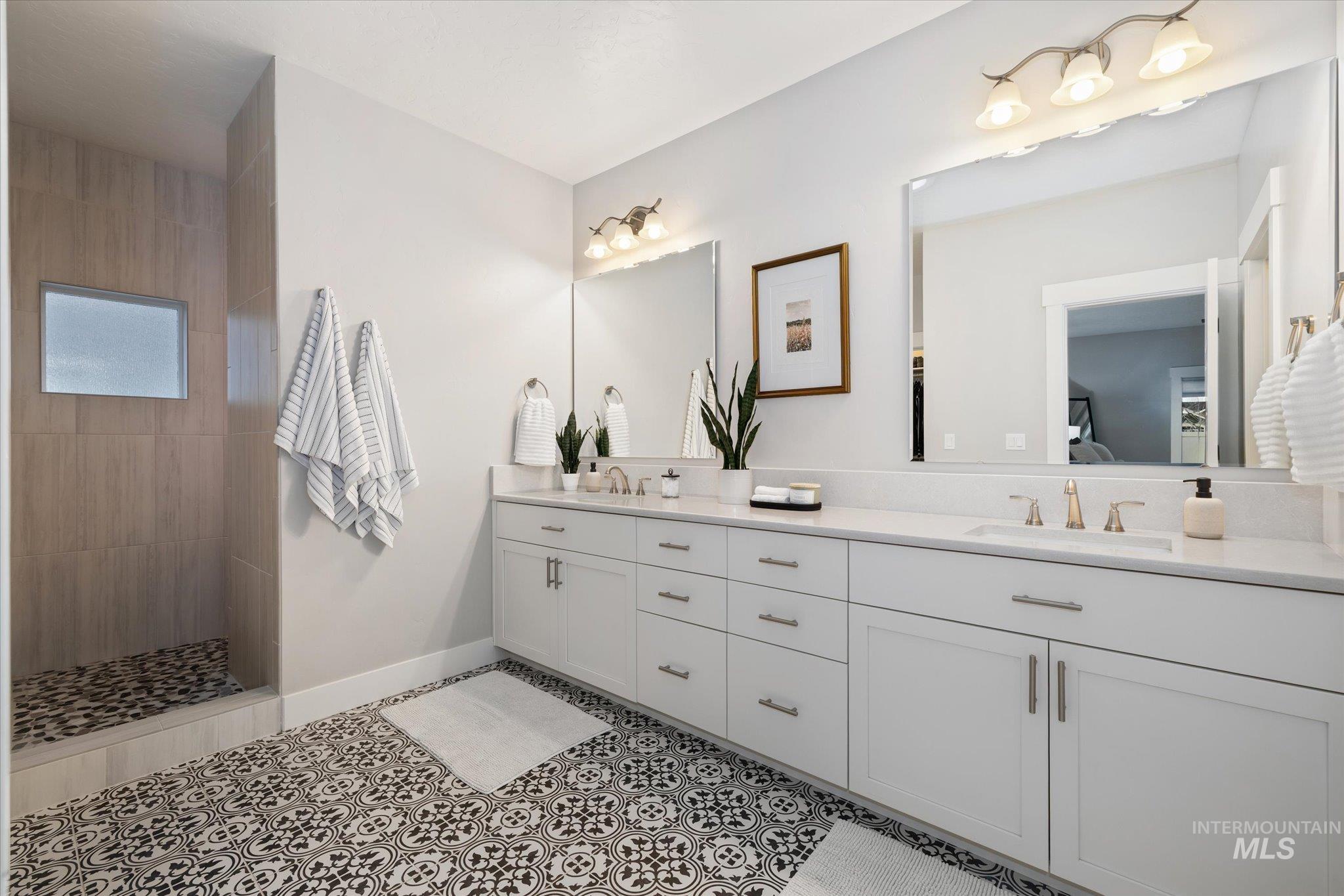 Bathroom featuring double vanity, walk in shower, ensuite bath, and light tile patterned flooring