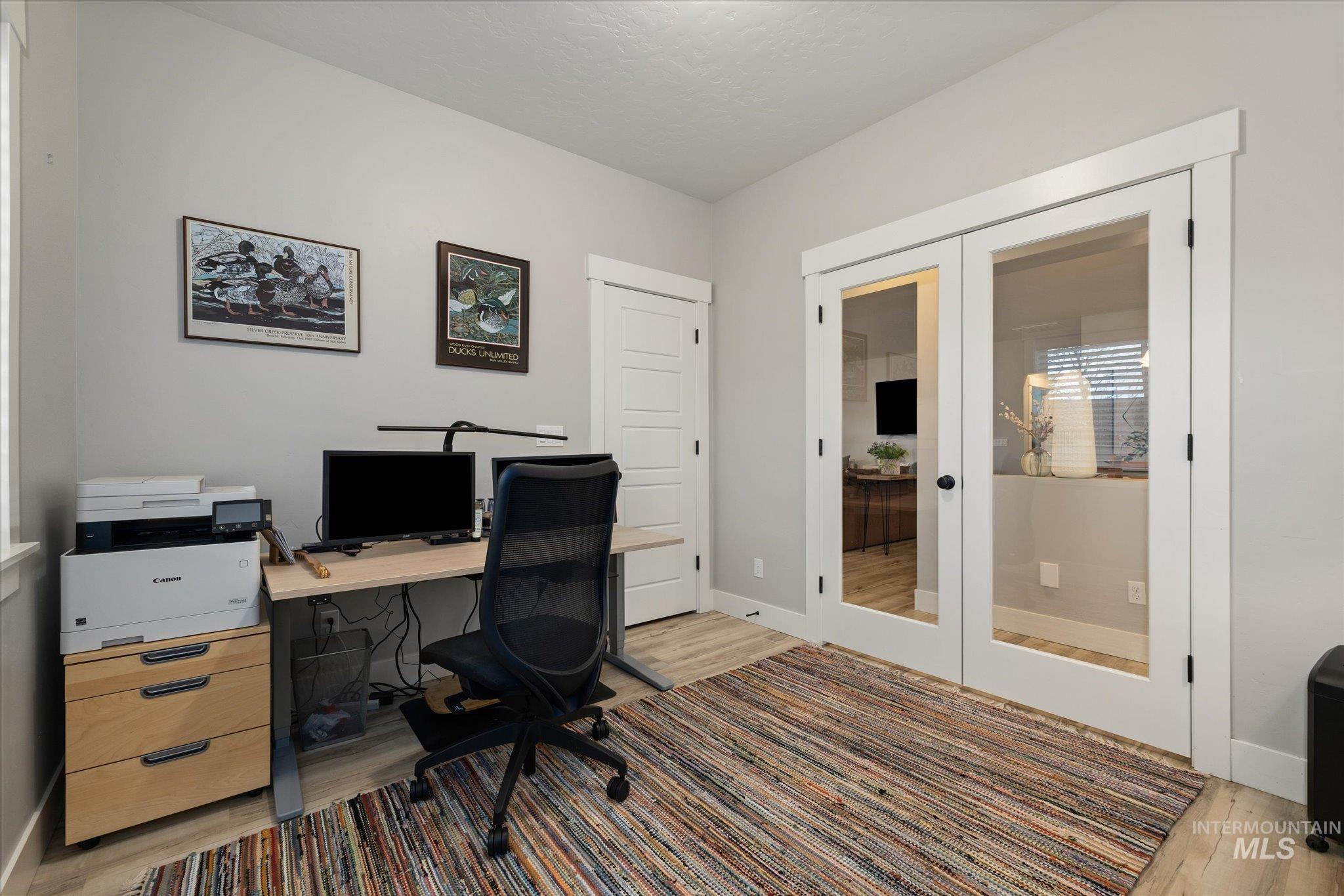 Office space featuring french doors and light wood-style floors