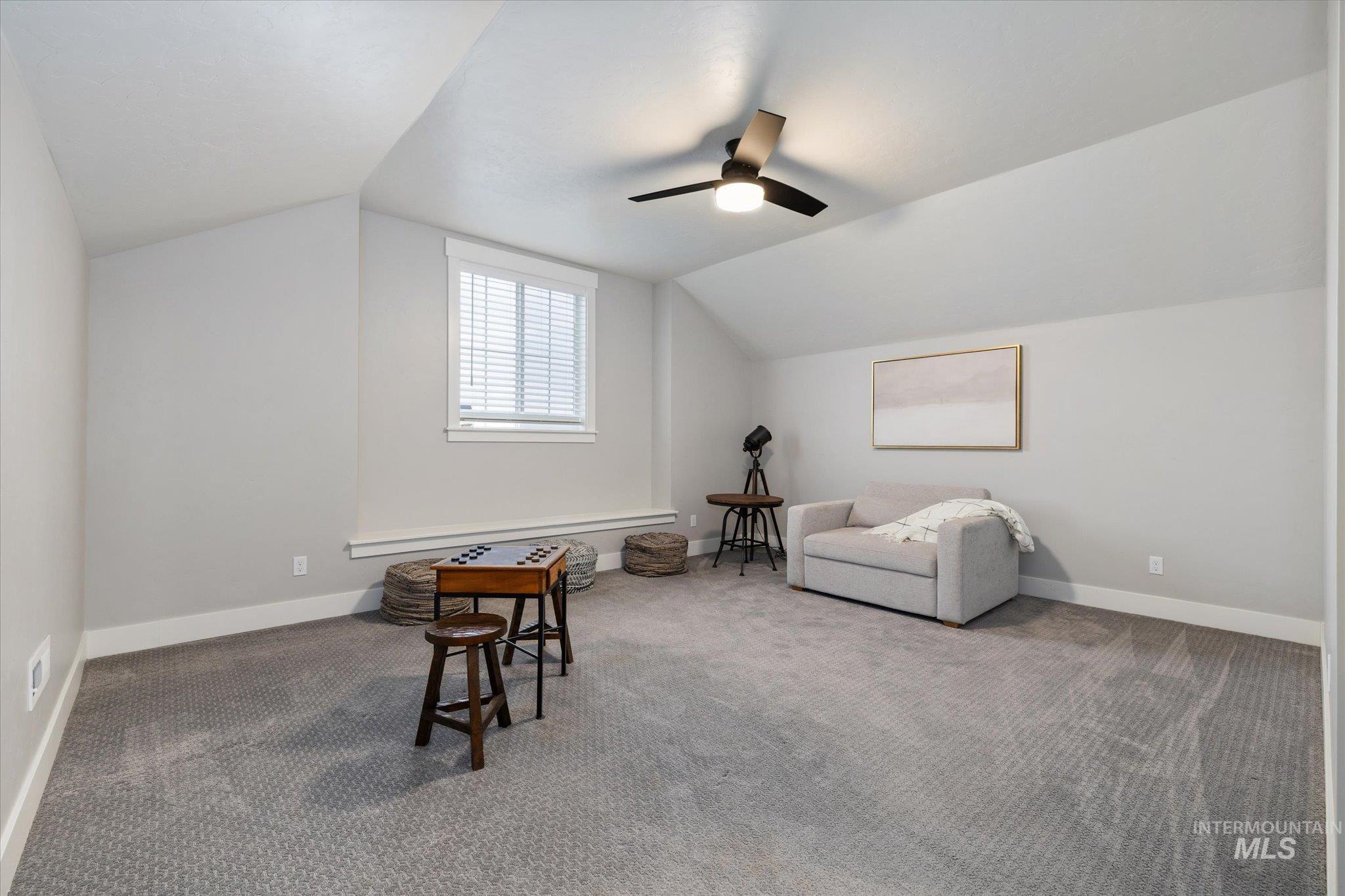 Living area with vaulted ceiling, carpet, and a ceiling fan