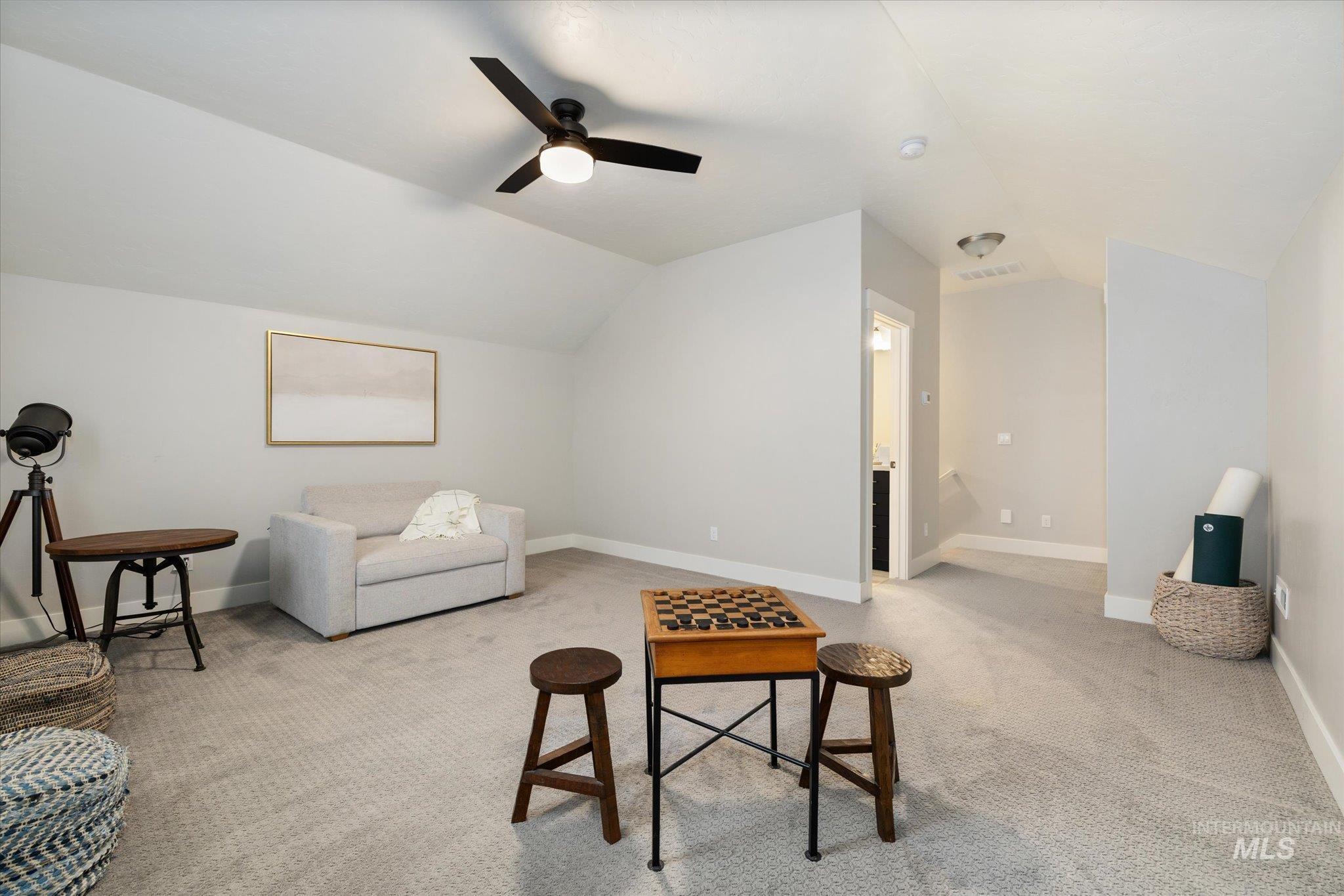 Living room with vaulted ceiling, light carpet, and ceiling fan
