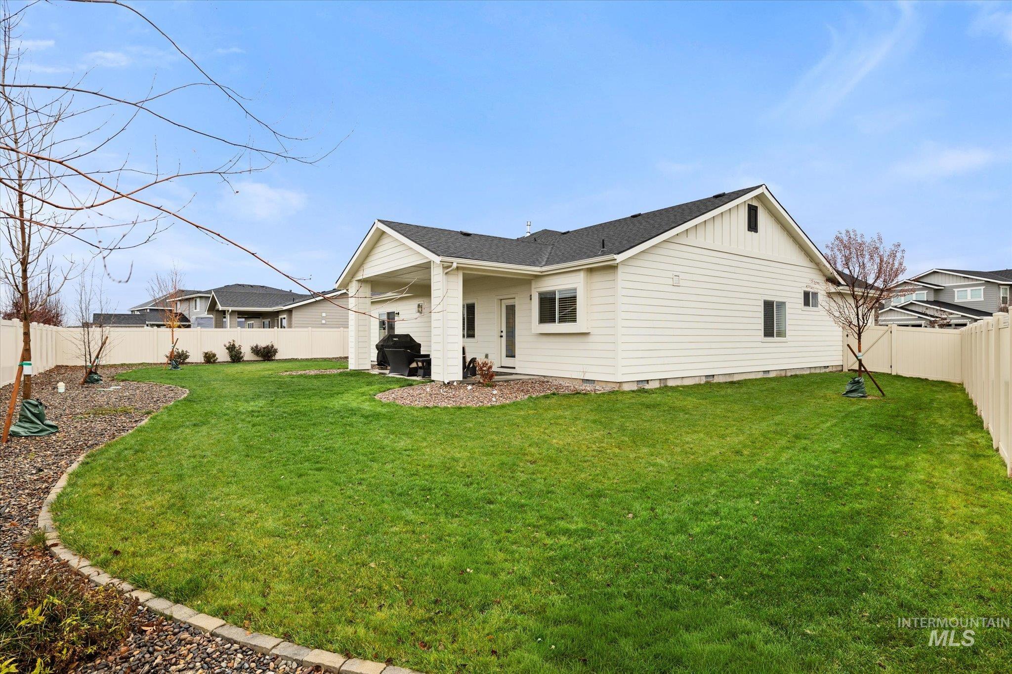 Rear view of house with a fenced backyard, a patio area, a shingled roof, and board and batten siding
