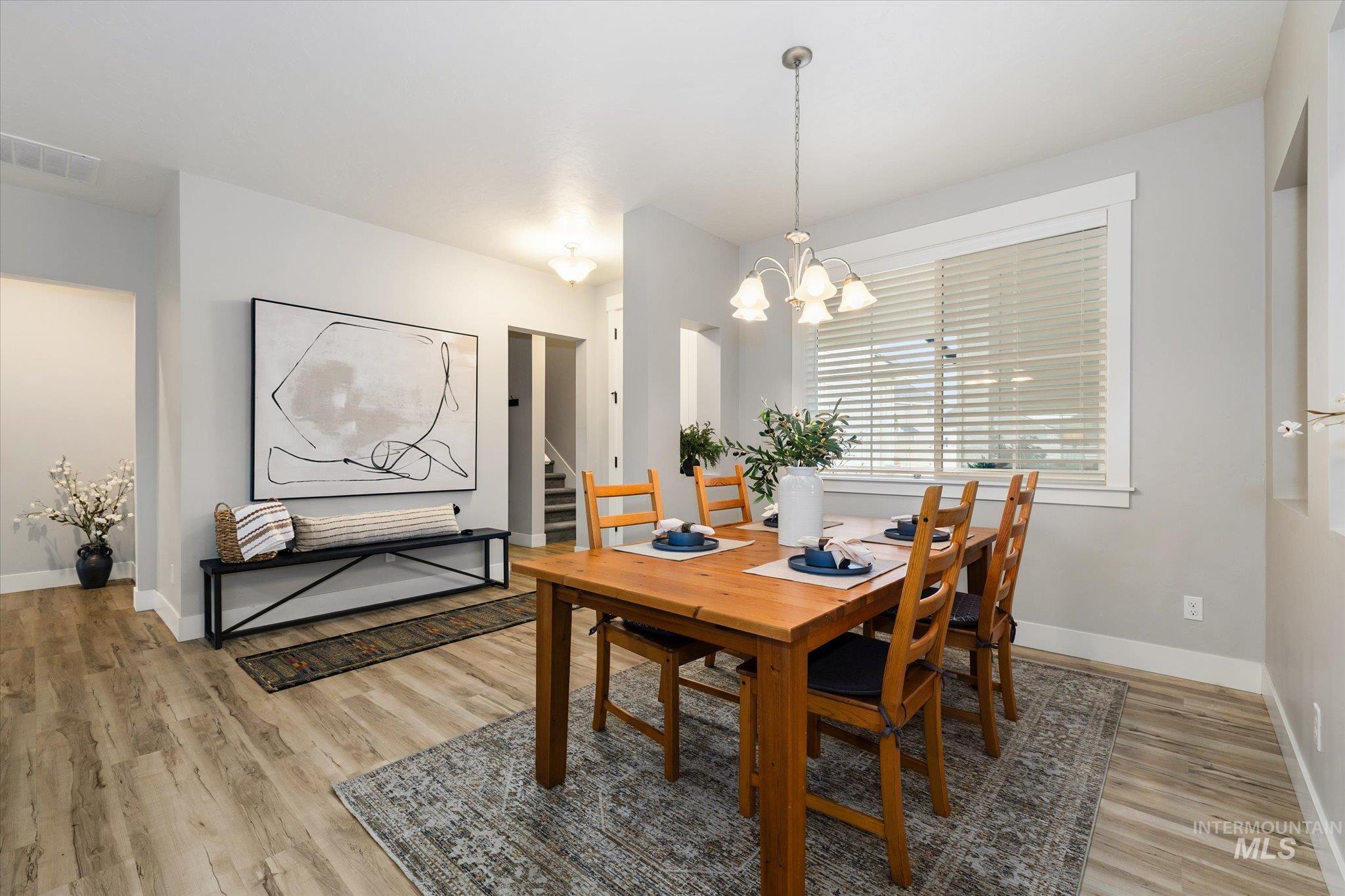 Dining area featuring stairway, light wood-style floors, and a chandelier