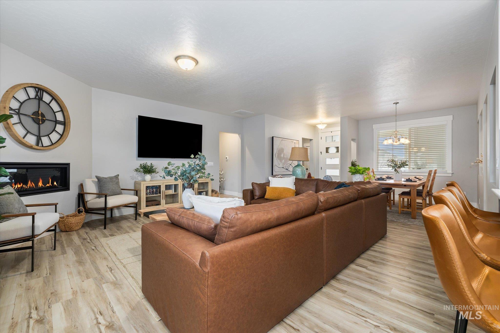Living room featuring a glass covered fireplace, light wood finished floors, and a chandelier