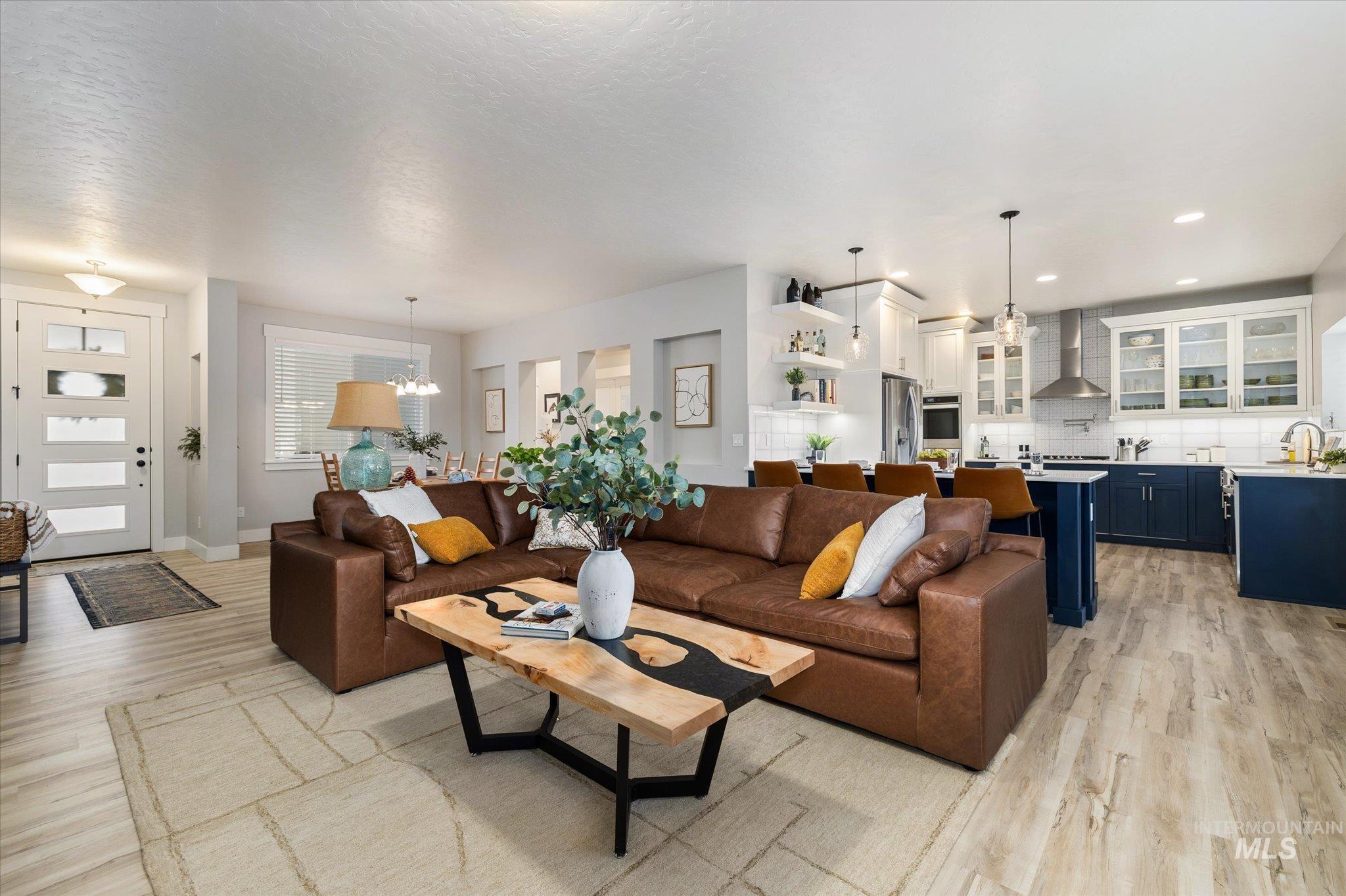 Living area with light wood-style floors, a chandelier, and a textured ceiling
