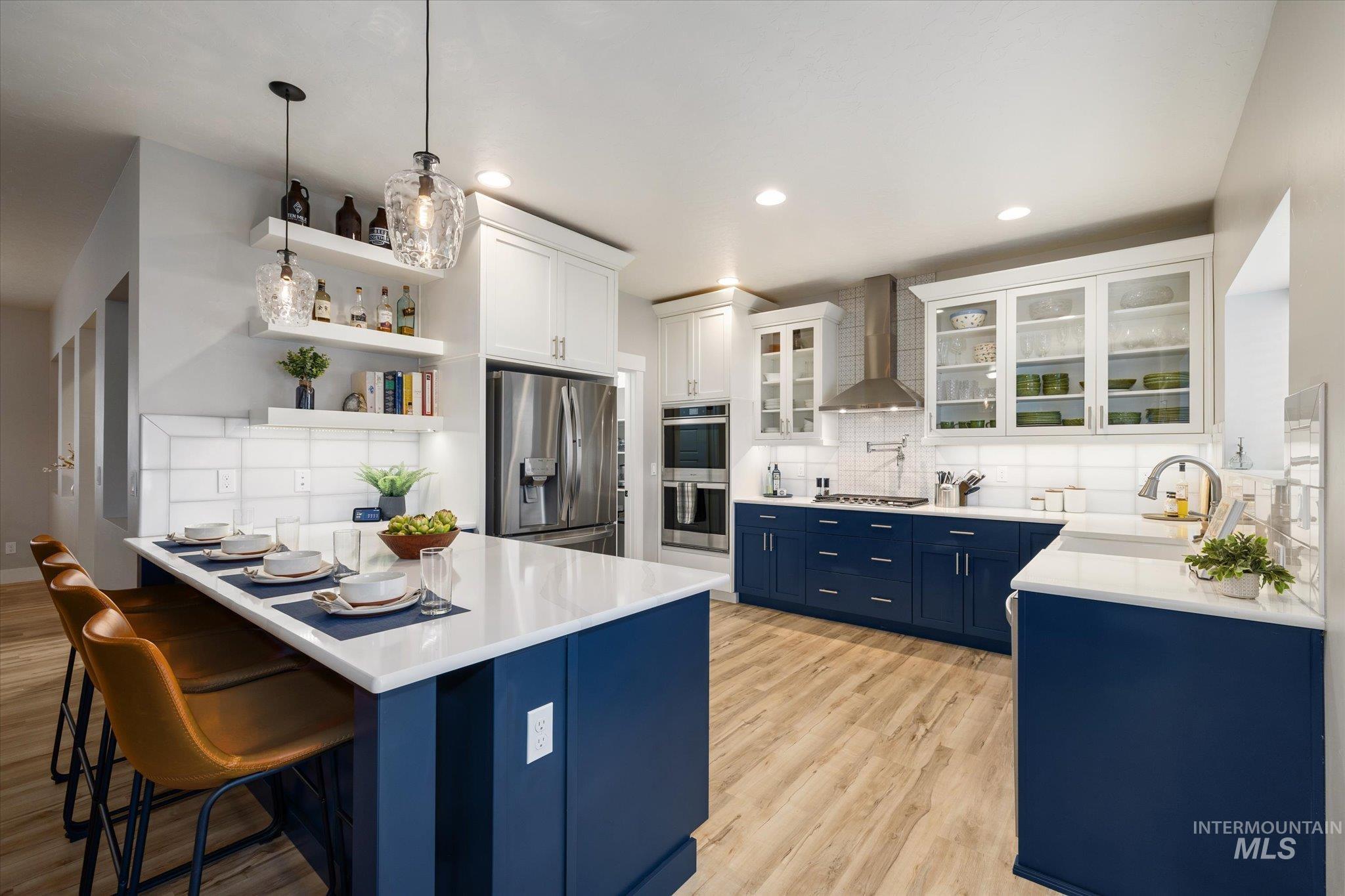 Kitchen featuring blue cabinetry, white cabinets, appliances with stainless steel finishes, light stone counters, and recessed lighting